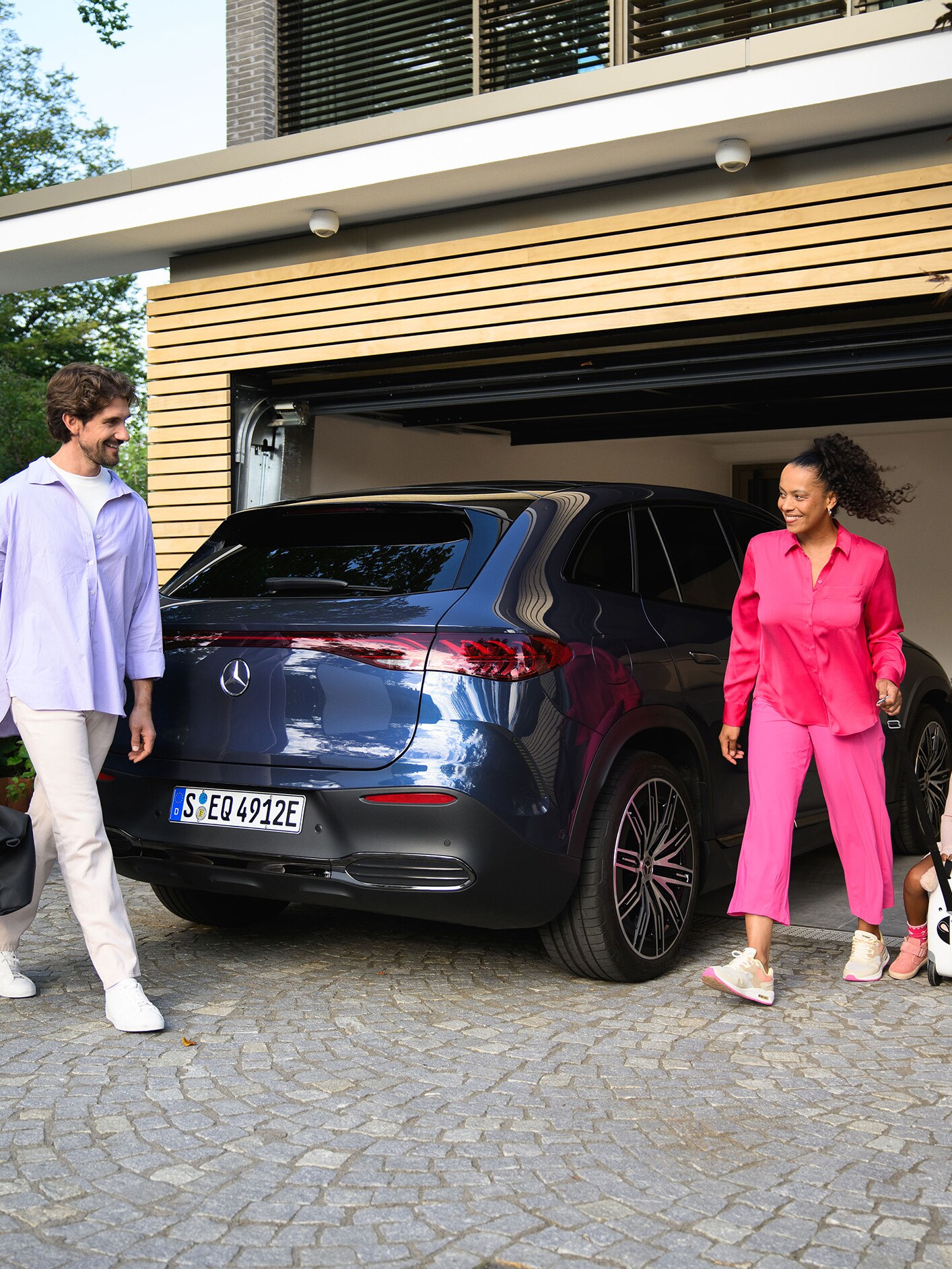 Deux personnes et un enfant se dirigeant vers leur véhicule Mercedes-Benz.