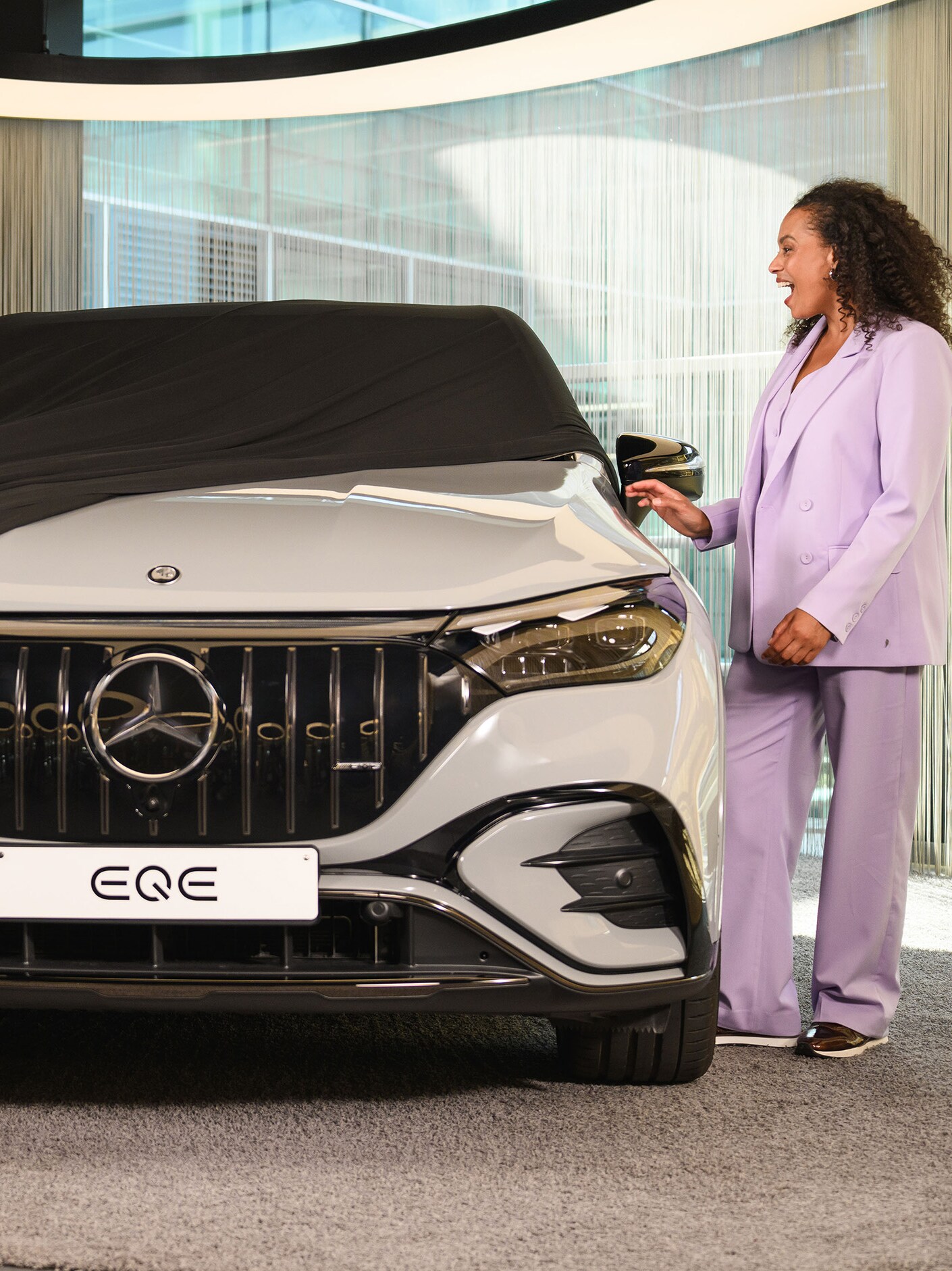 Deux personnes et un enfant retirant une housse d'un nouveau véhicule Mercedes-Benz dans un showroom.