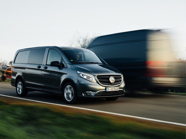 Deux Mercedes-Benz Vans différents sont montrés en train de se croiser sur une route de campagne.