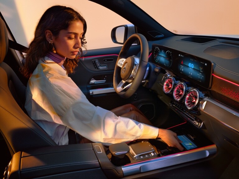 Une femme charge son smartphone sans fil dans le vide-poches de sa Mercedes-Benz.