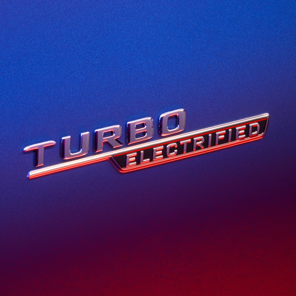 TURBO E PERFORMANCE-badge op de voorspatscherm, verlicht door rood licht.
