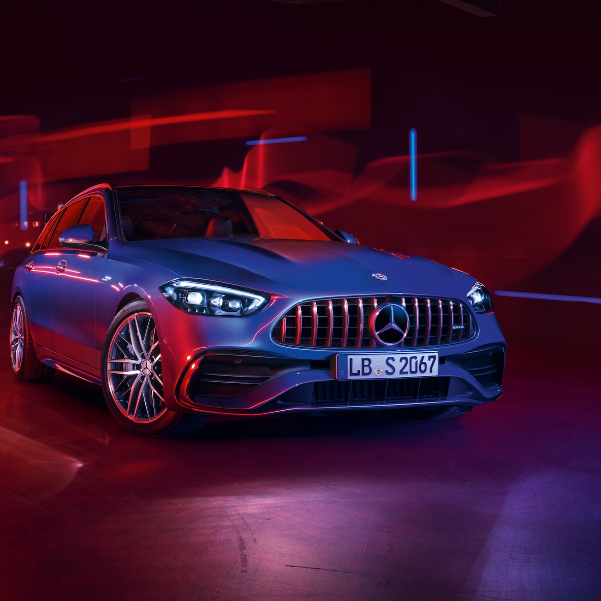 Vooraanzicht van de Mercedes-AMG C 43 tegen een rode achtergrond.