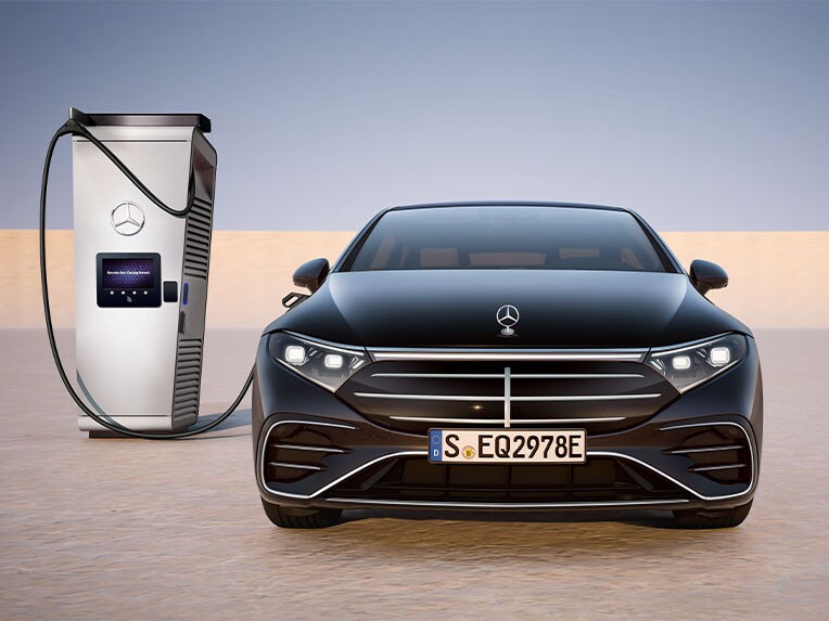 Vooraanzicht van de EQS Berline van Mercedes-Benz die bij een publiek oplaadpunt wordt opgeladen.