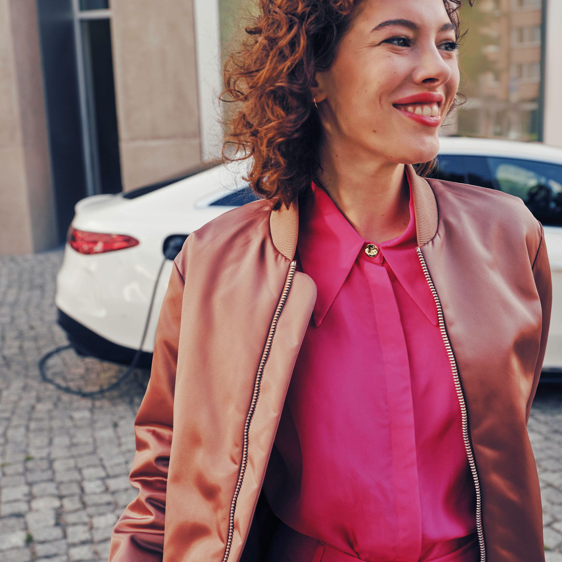 Changement de fiscalité en 2023 Une femme marche à côté d'une Mercedes-Benz EQS blanche.