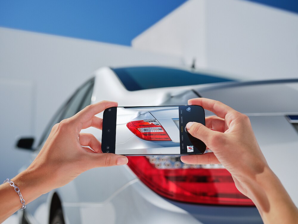 Quelqu'un photographie un dommage sur un véhicule Mercedes-Benz avec son smartphone.