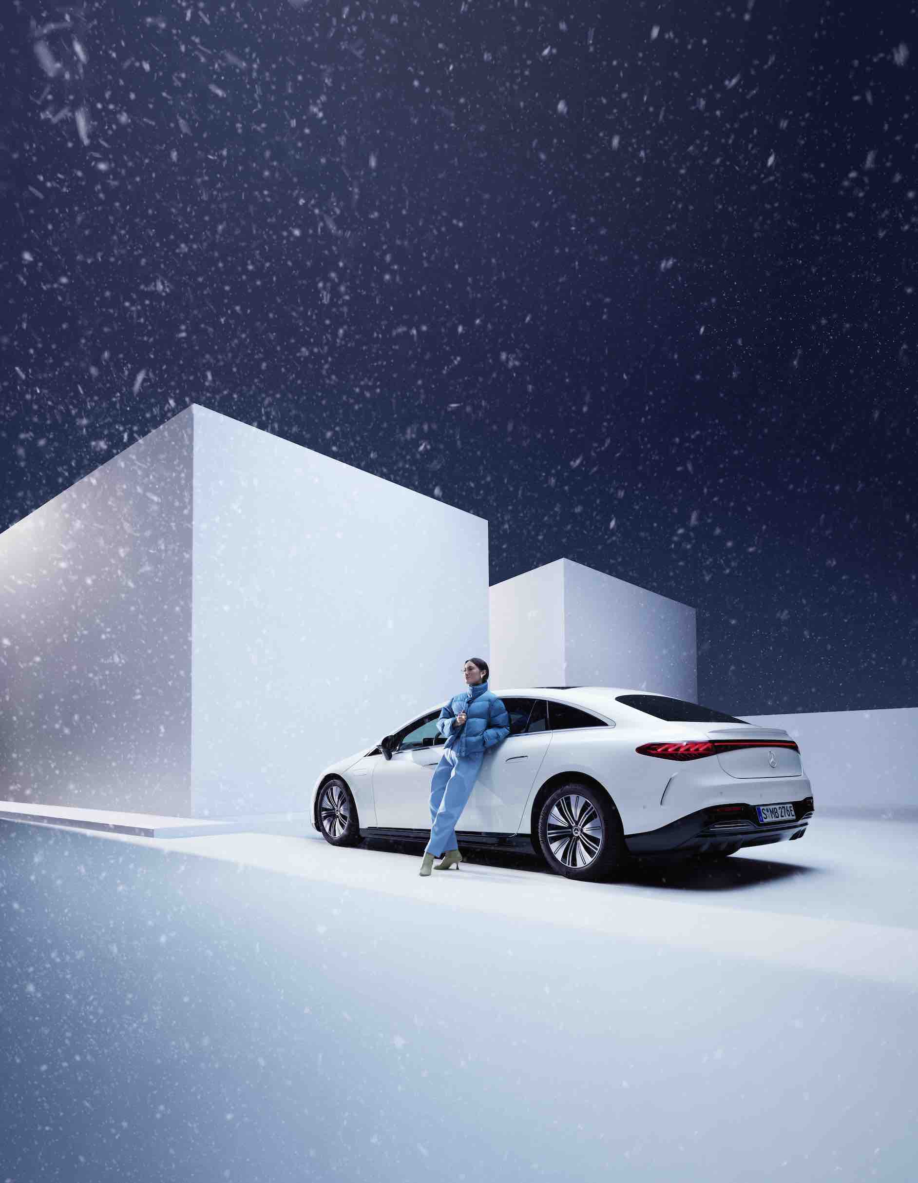 Mercedes-Benz | Originele verzorgingsproducten Een vrouw leunt tegen haar Mercedes-Benz aan terwijl het sneeuwt.