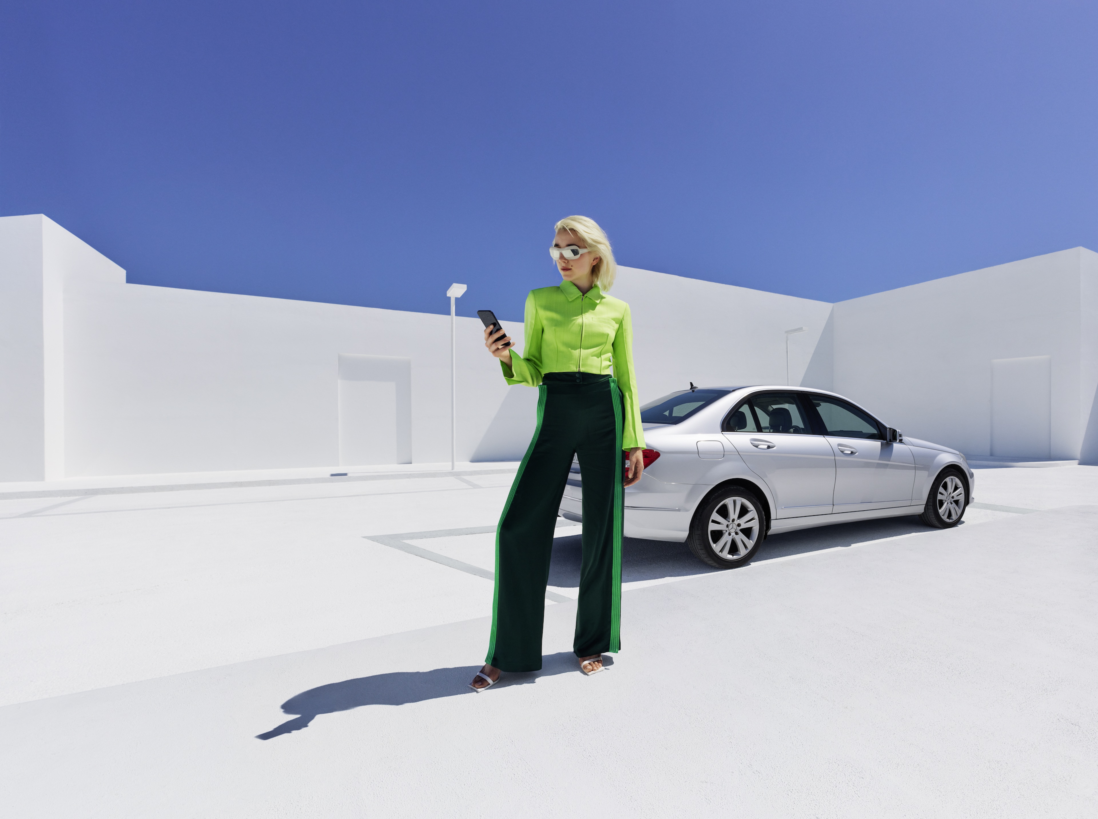 Mercedes-Benz Adapter Une femme se tient devant sa Mercedes-Benz et consulte son smartphone.