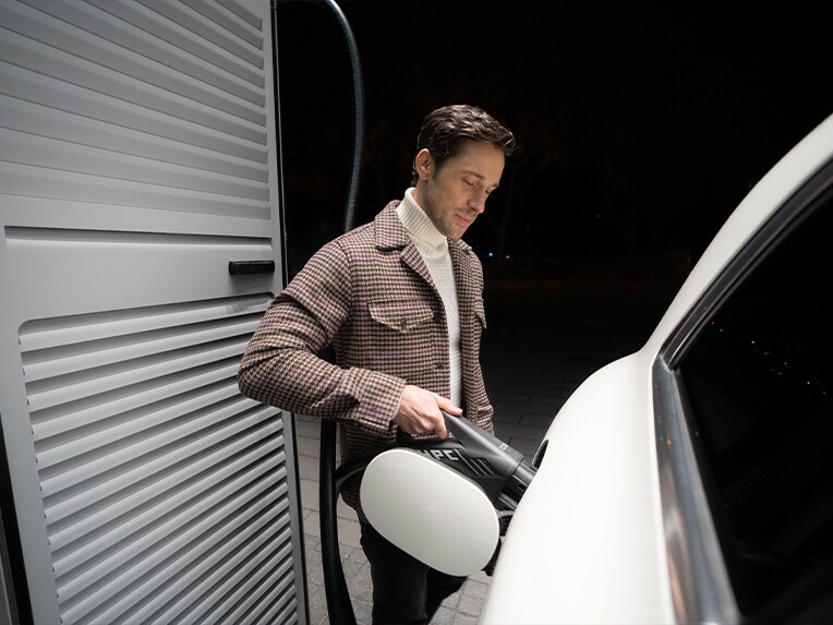 Un homme recharge sa voiture électrique Mercedes-Benz à une borne de recharge.