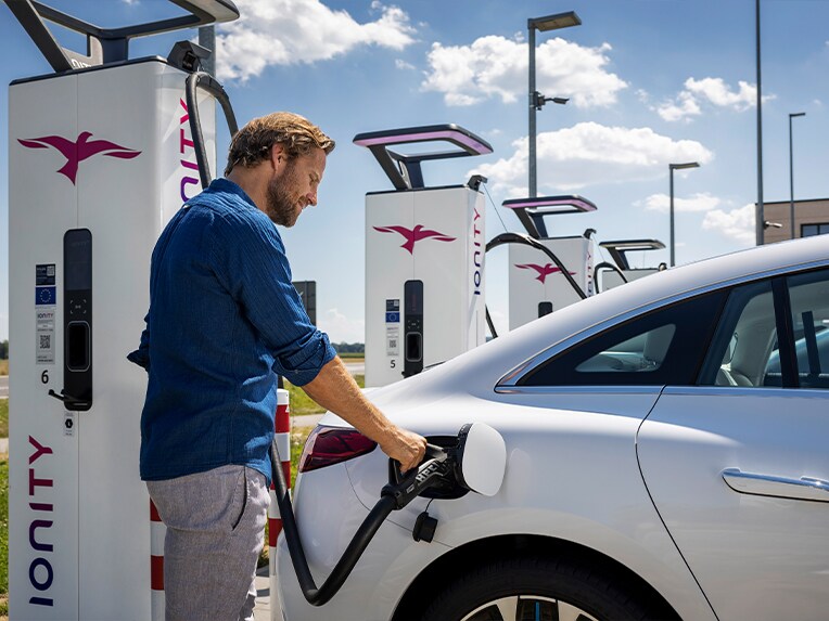 Un homme rechargeant sa Mercedes-Benz EQS à une borne de recharge IONITY Unlimited.