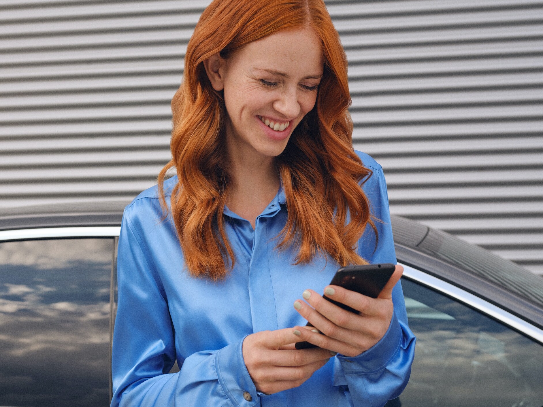 Une femme se connecte à sa Mercedes-Benz via l’application Mercedes me sur son smartphone.