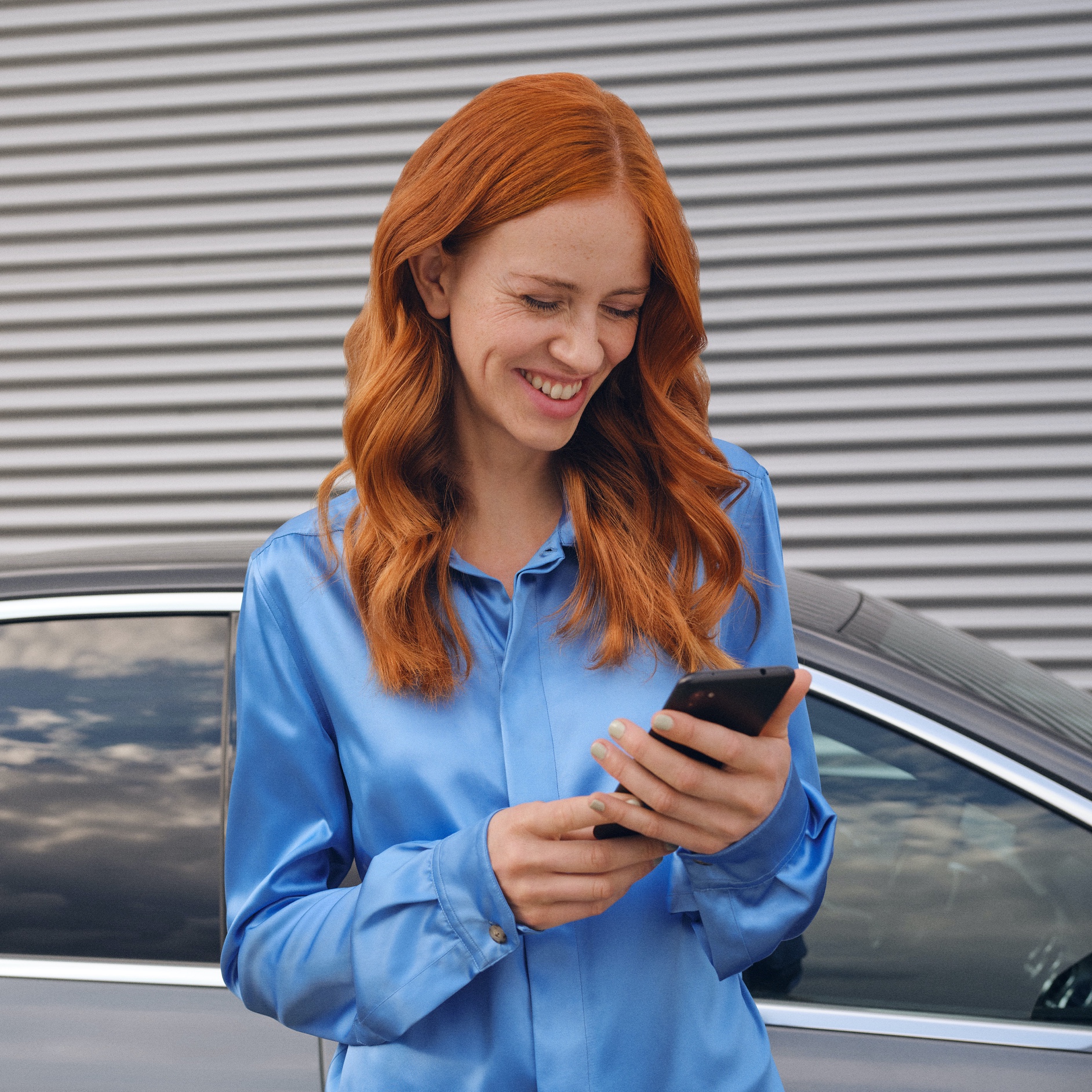 Une femme se connecte à sa Mercedes-Benz via l’application Mercedes me sur son smartphone. Une femme se connecte à sa Mercedes-Benz via l’application Mercedes me sur son smartphone.