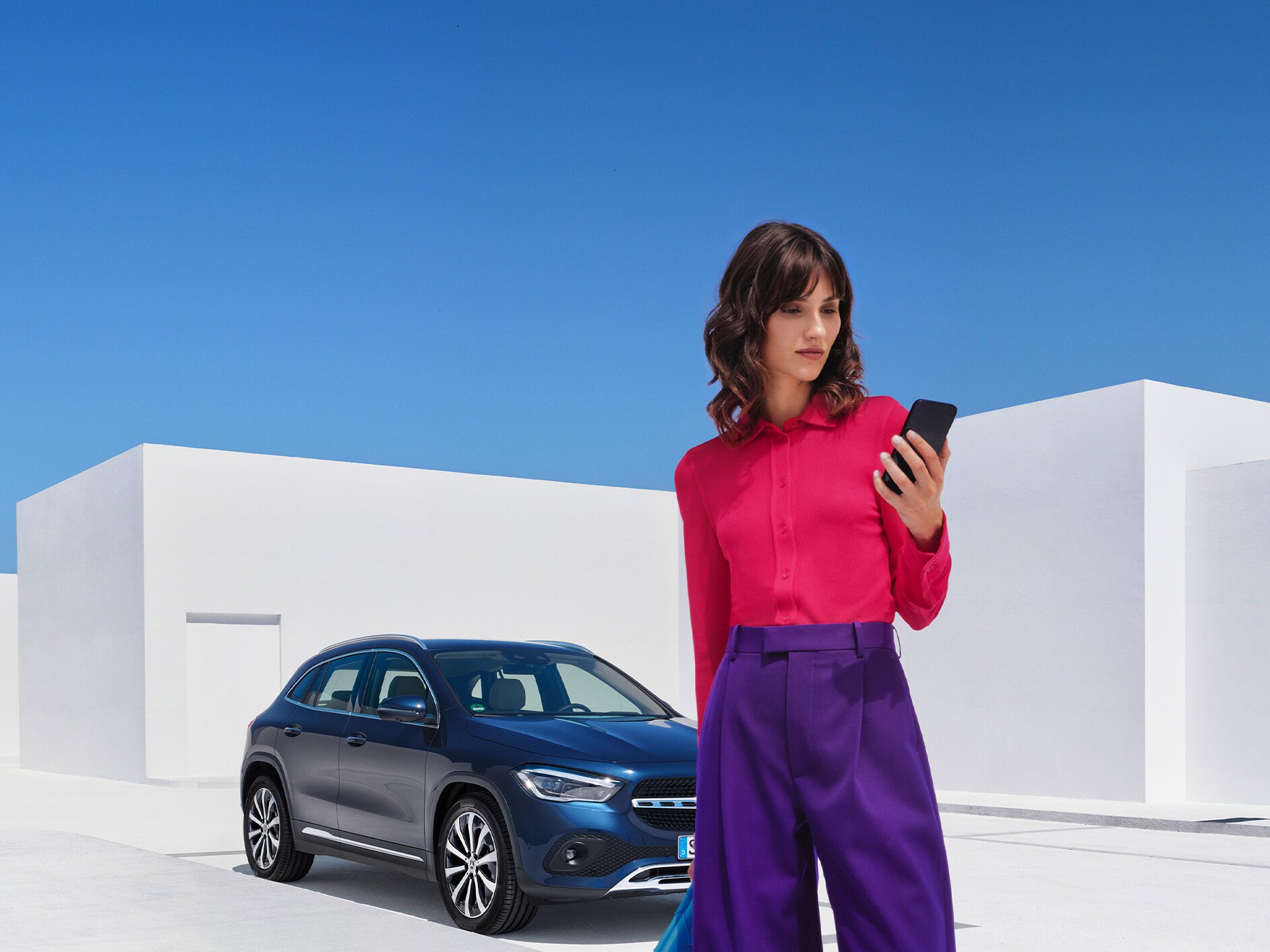 Een vrouw brengt via de Mercedes Me app op haar smartphone een verbinding met haar Mercedes-Benz tot stand.