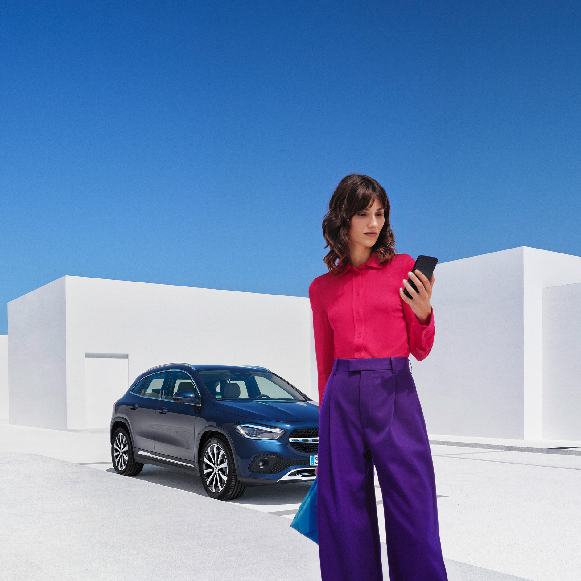 Zo werkt het | Apps | Mercedes me Een vrouw brengt via de Mercedes Me app op haar smartphone een verbinding met haar Mercedes-Benz tot stand.