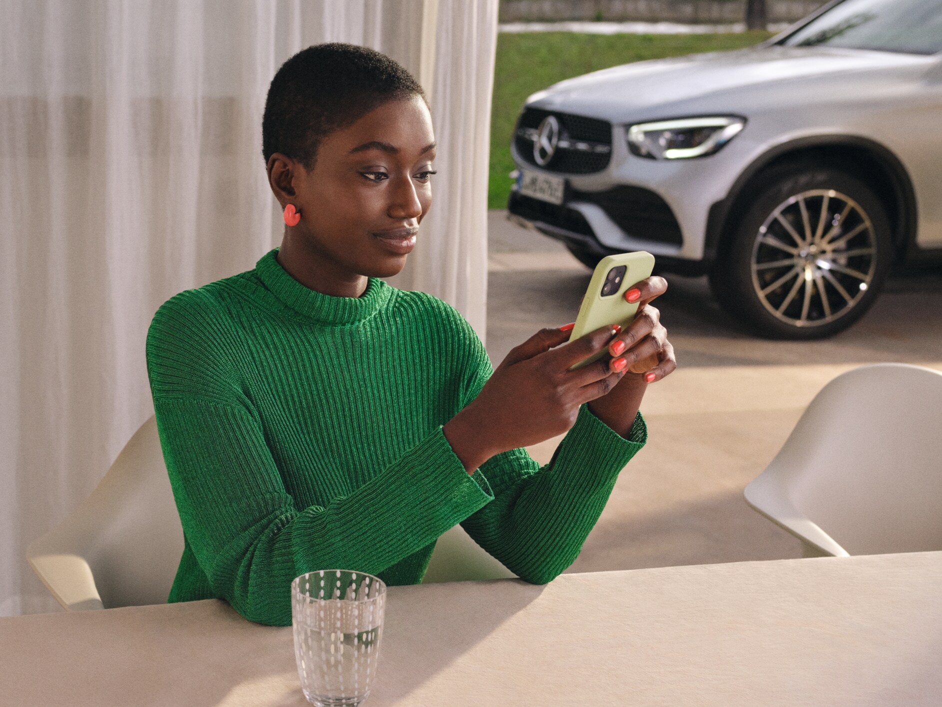 Een vrouw controleert met haar smartphone de status van haar auto.