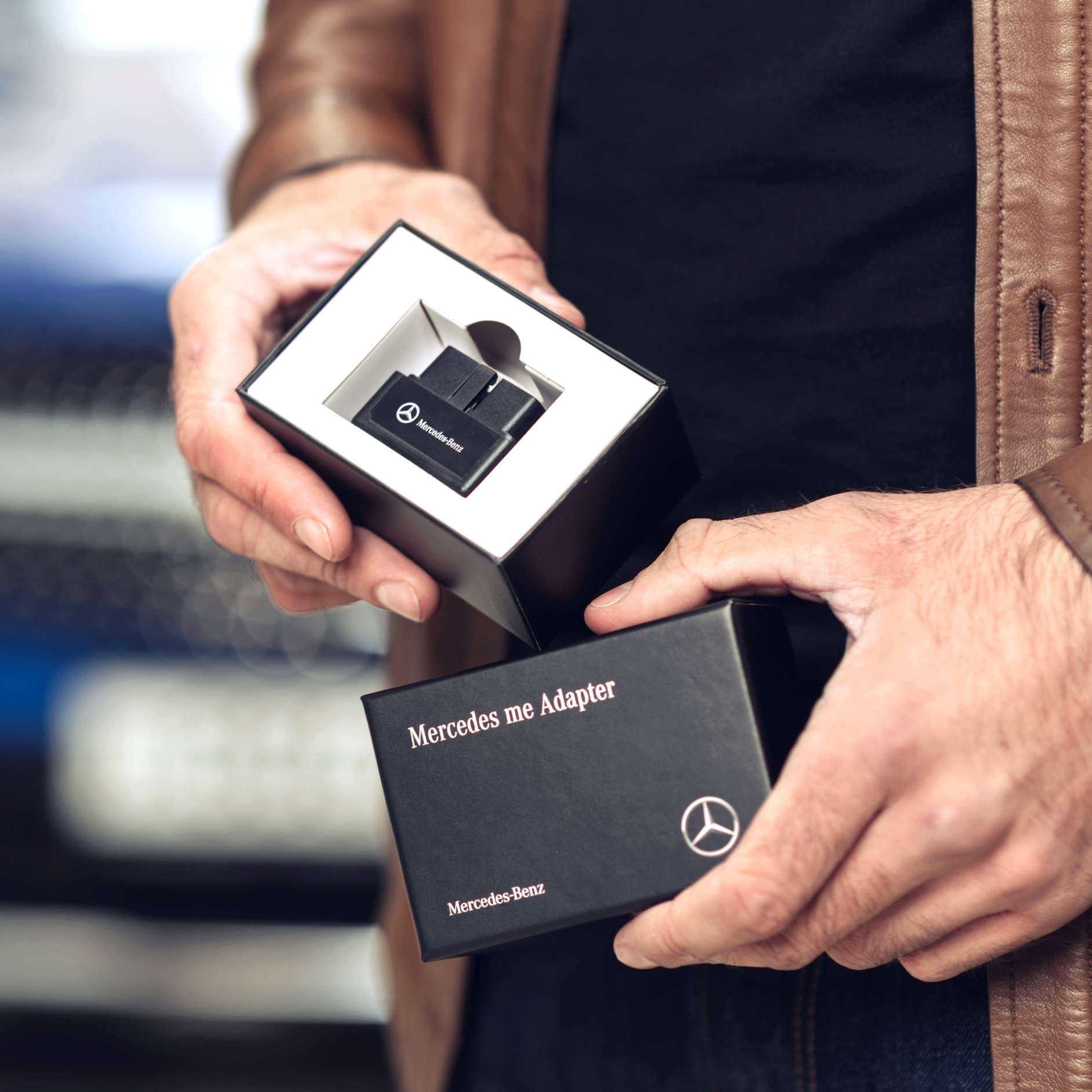 Un homme déballe le Mercedes me Adapter pour sa Mercedes-Benz afin de pouvoir utiliser des offres digitales dans son véhicule. Un homme déballe le Mercedes-Benz Adapter pour sa Mercedes-Benz afin de pouvoir utiliser des offres digitales dans son véhicule.