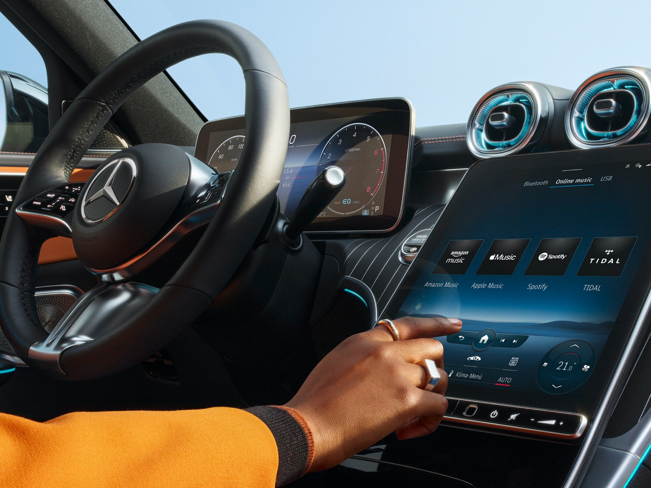 Une personne choisit sur le système multimédia MBUX d’une Mercedes-Benz parmi les services de streaming audio Amazon Music, Apple Music, Spotify et TIDAL celui qu’elle souhaite utiliser.