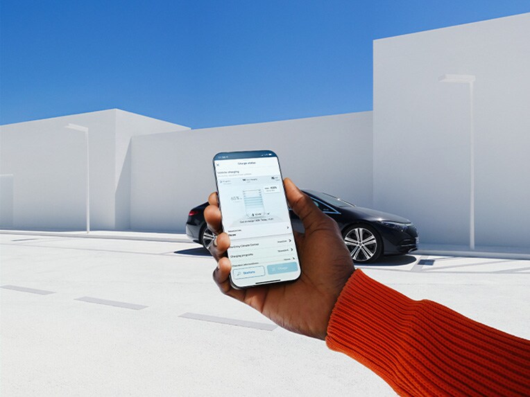 Een vrouw gebruikt de Mercedes me App op haar smartphone om een verbinding met haar Mercedes-Benz tot stand te brengen.