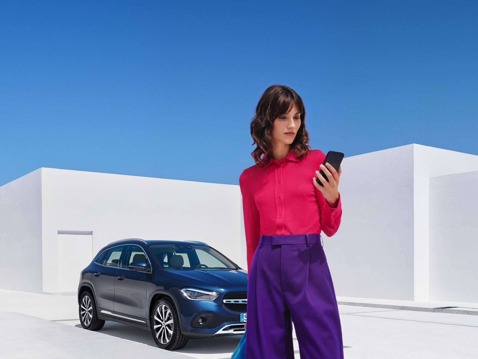 Een vrouw brengt via de Mercedes-Benz app op haar smartphone een verbinding met haar Mercedes-Benz tot stand.