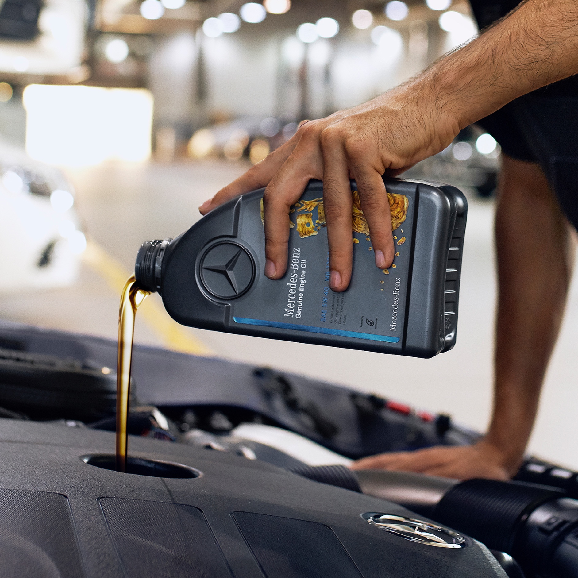 Huile moteur | Mercedes-Benz Une personne versant de l'huile moteur dans une Mercedes-Benz.