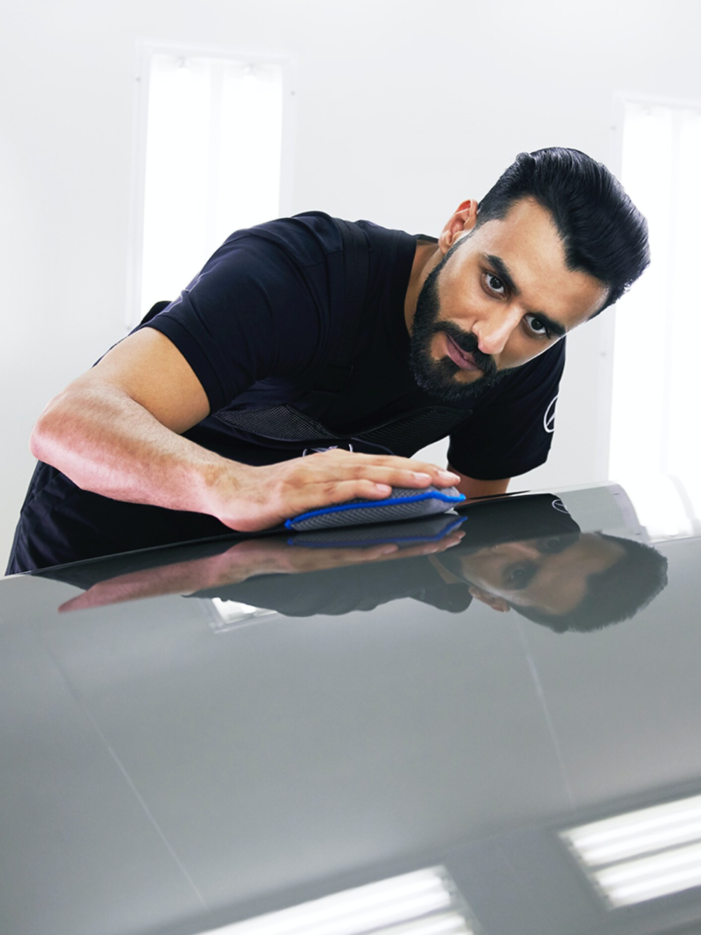 Een Mercedes-Benz technicus controleert de motorkap op kleine beschadigingen.