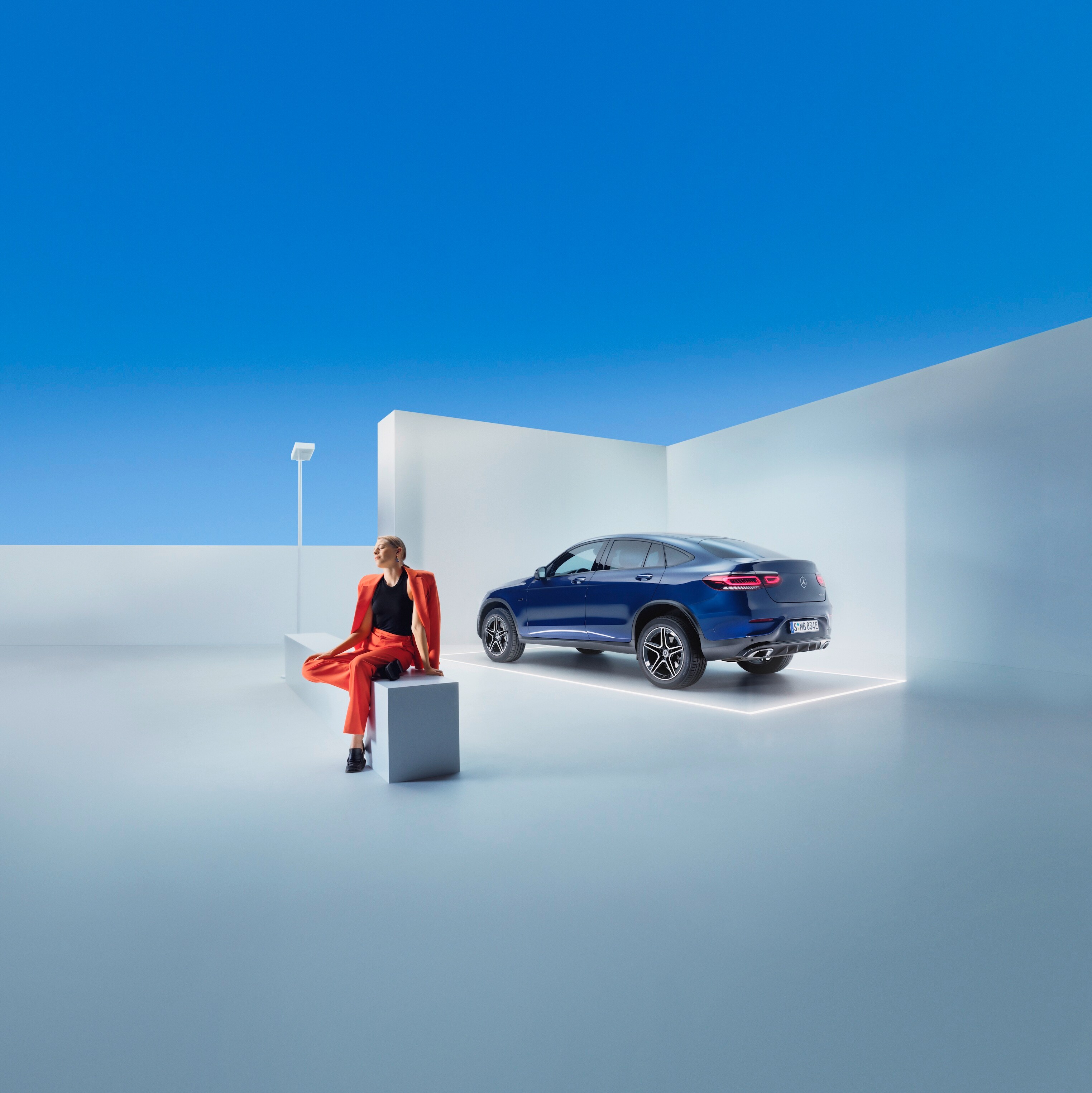 Een vrouw zit op een bank vóór een Mercedes-Benz.