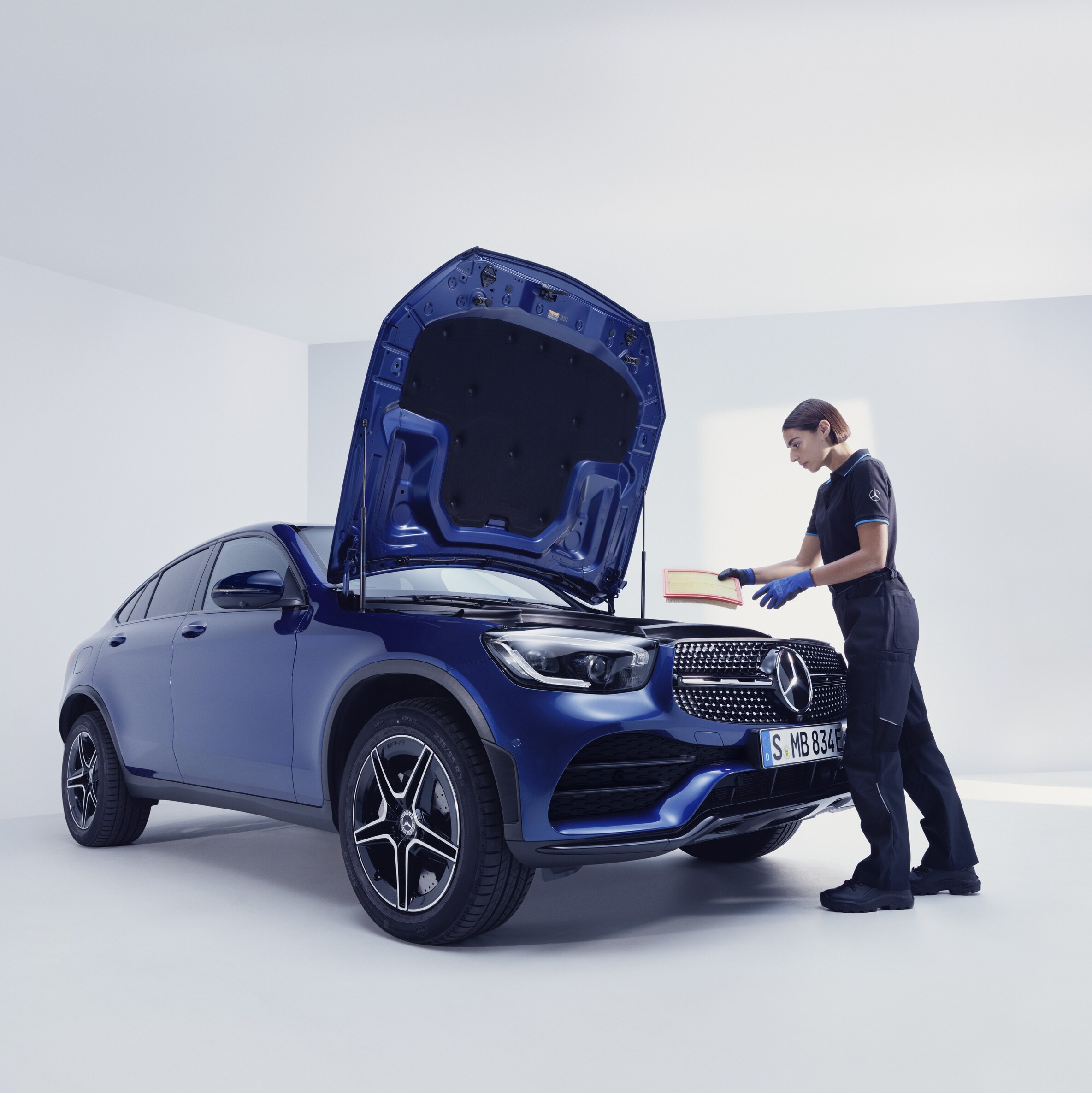 Een Mercedes-Benz technicus en een man staan voor de geopende motorkap van een Mercedes-Benz.