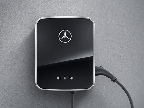 Un boîtier mural Mercedes-Benz Wallbox noir avec câble de recharge est fixé au mur.