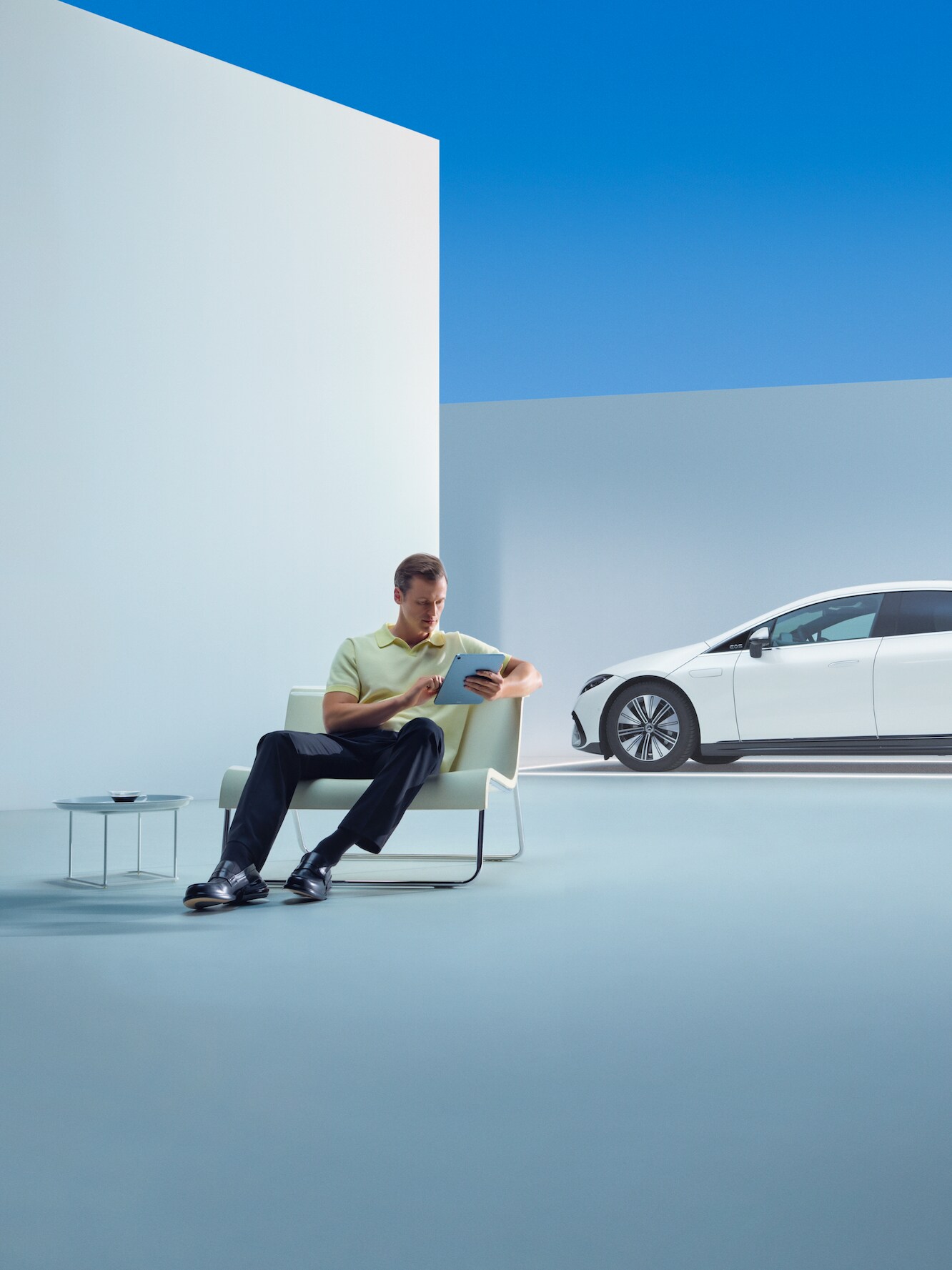 Een ontspannen man zit met zijn tablet voor zijn Mercedes.