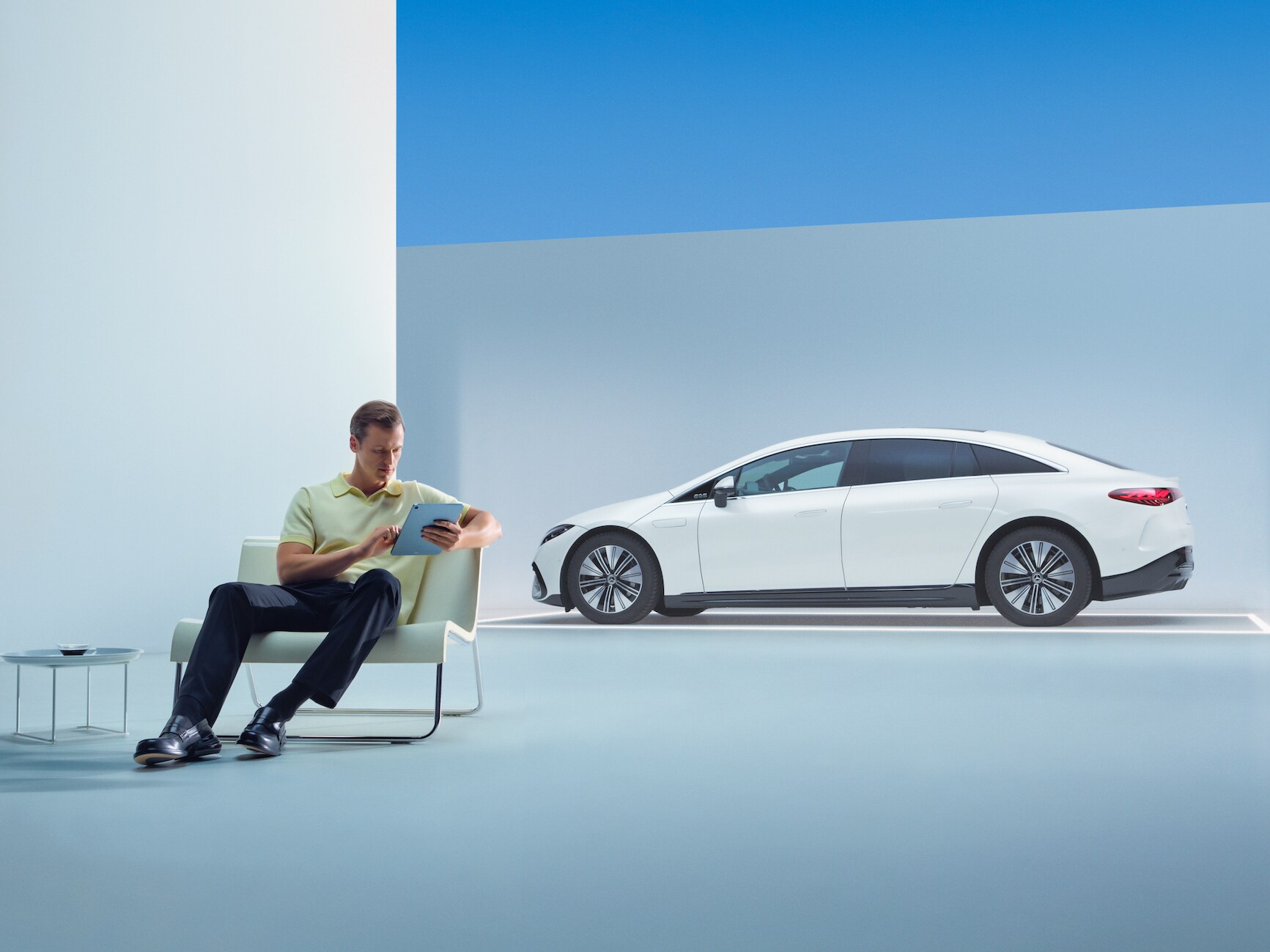 Un homme détendu est assis devant sa Mercedes avec sa tablette.