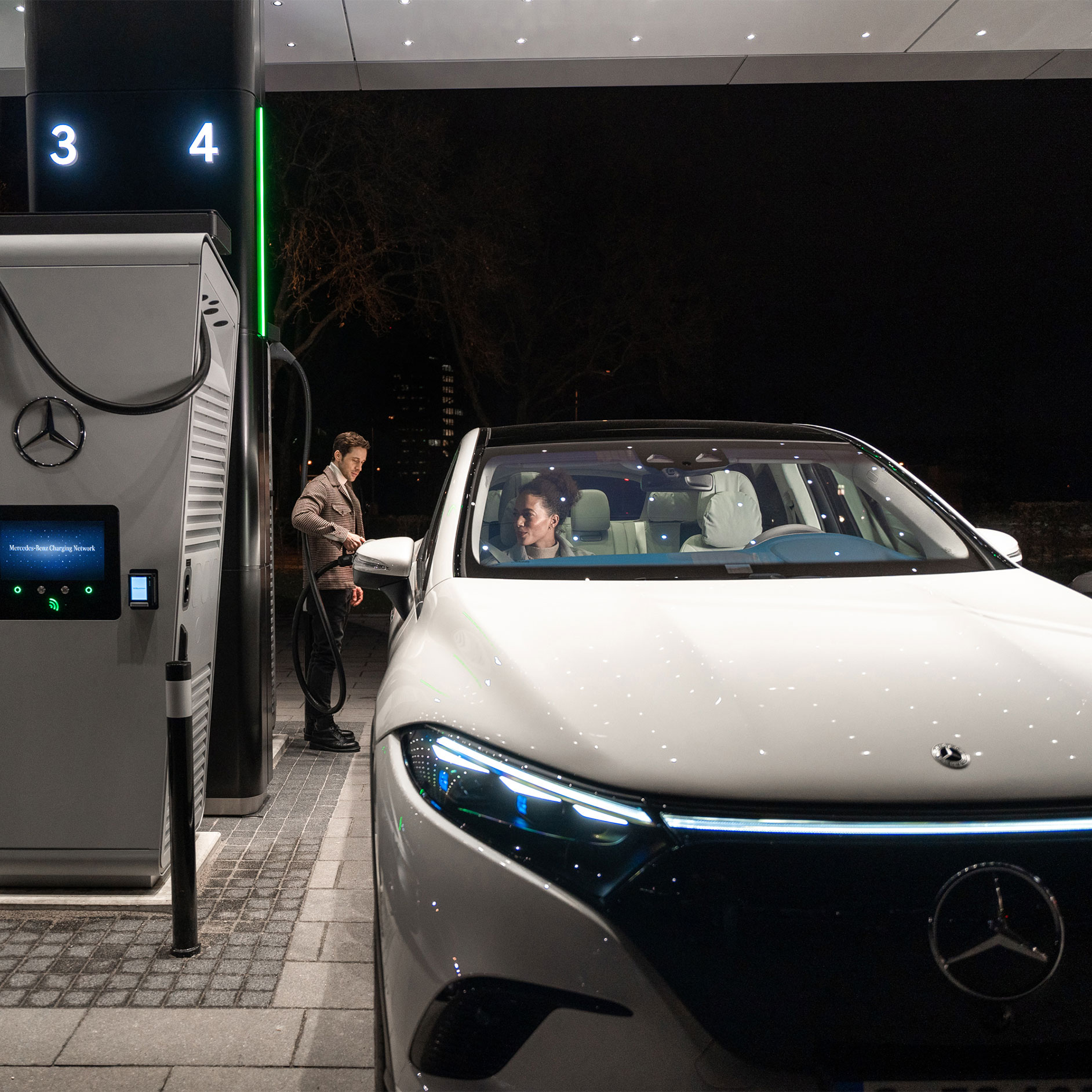 Recharge publique | Recharge | Mercedes-Benz Une personne rechargeant une Mercedes-Benz EQS SUV sur une borne de recharge.