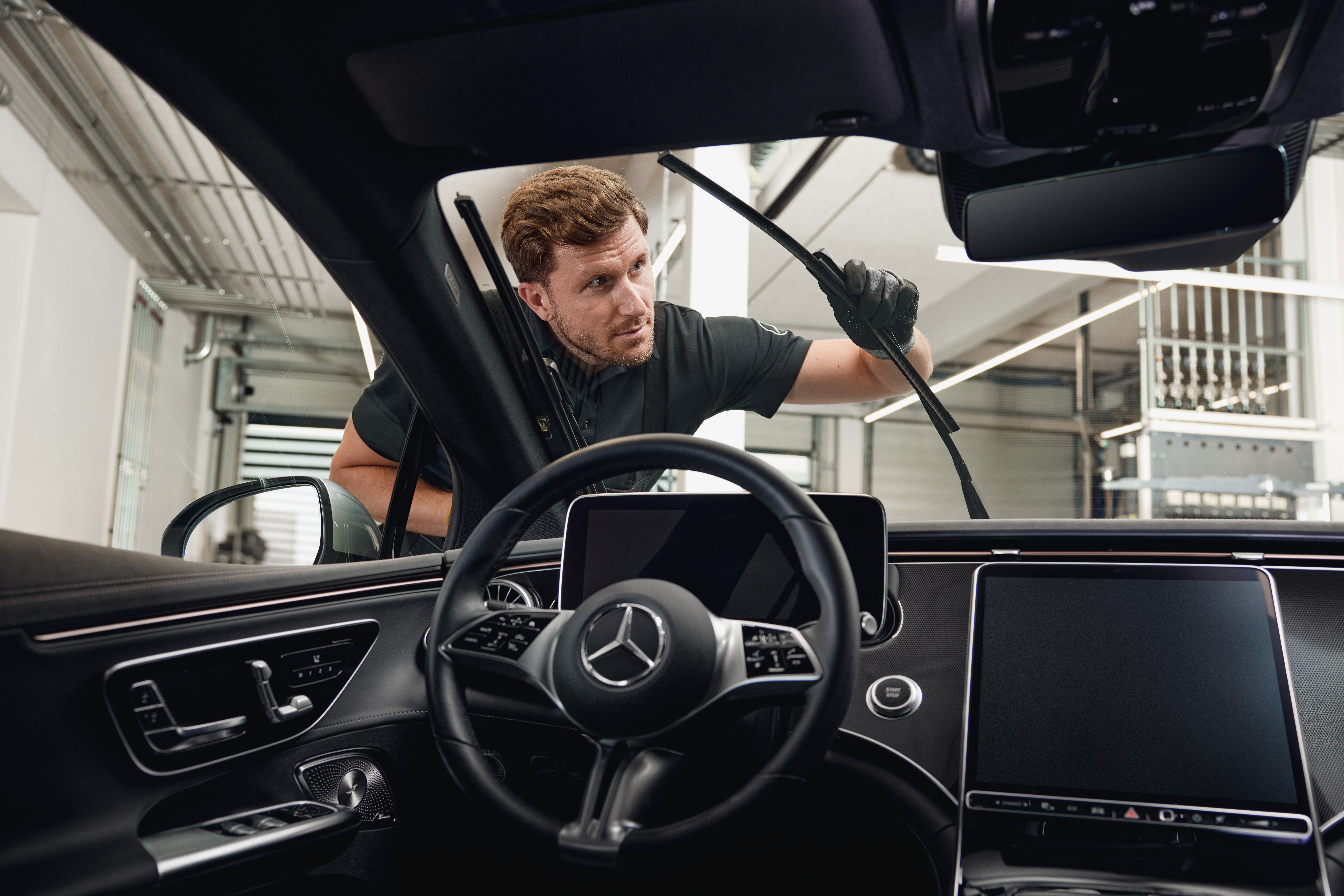 Mercedes-Benz originele ruitenwisserbladen Binnenzicht van een Mercedes-Benz voertuig met een monteur die originele ruitenwisserbladen vervangt.