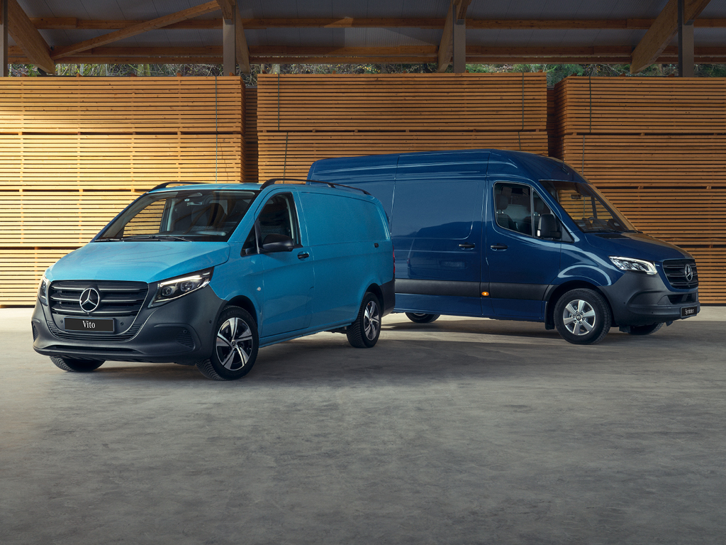 Mercedes-Benz bestelwagens in een loods Twee blauwe Mercedes-Benz bestelwagens in een houten loods.