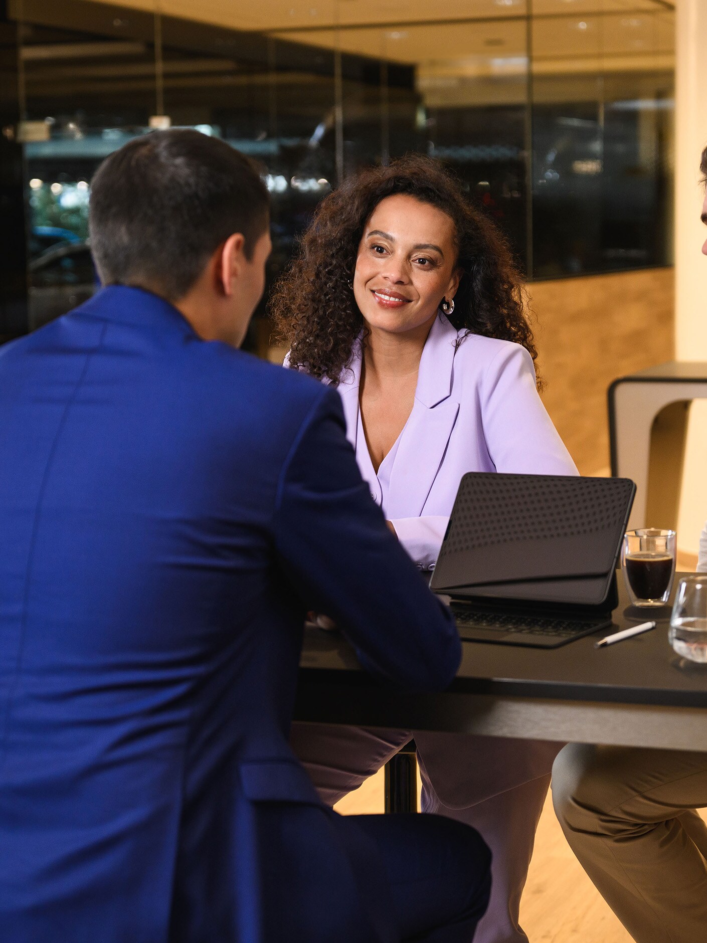 Drie personen zitten aan een tafel en zijn in gesprek.​