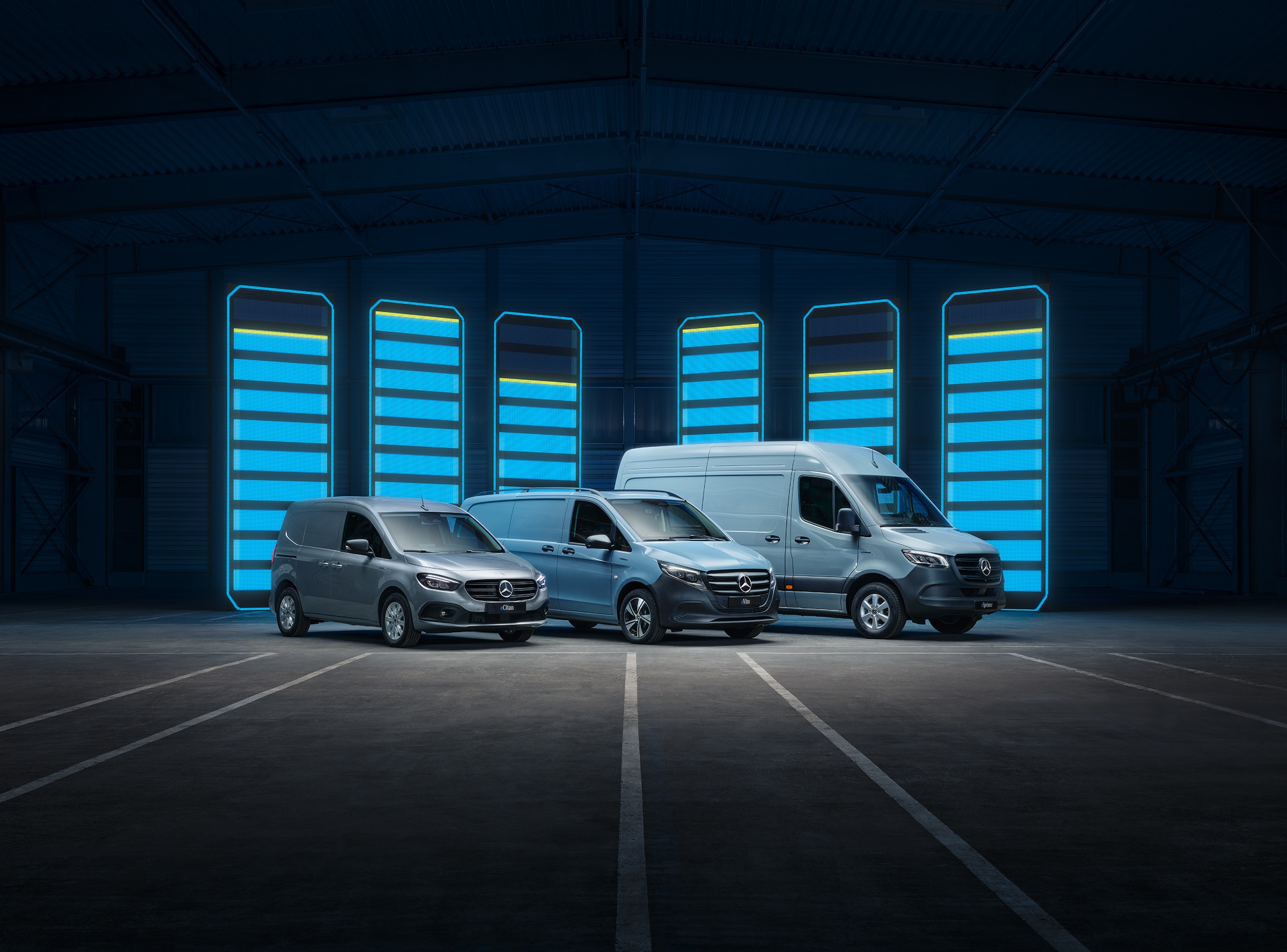Het assortiment elektrische bestelwagens van Mercedes-Benz | Geschiedenis van bedrijfswagens | Mercedes-Benz Het assortiment elektrische bestelwagens van Mercedes-Benz wordt tentoongesteld in een futuristisch magazijn met verlichte oplaadpunten