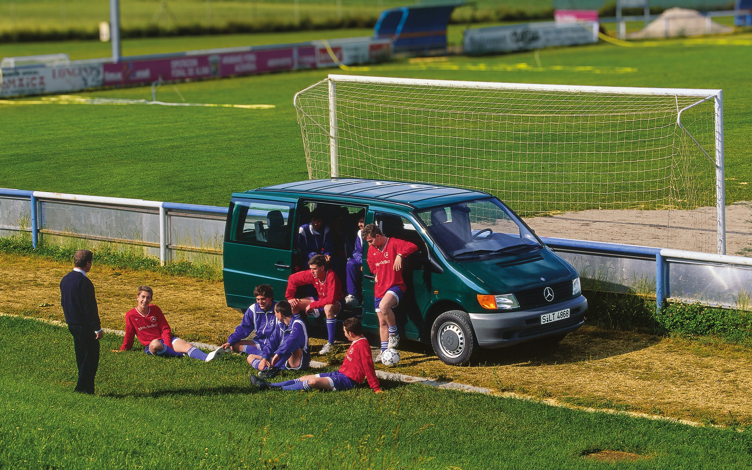 La première génération de Mercedes-Benz Vito | Histoire des véhicules industriels | Mercedes-Benz Un Vito première génération garé à côté d'un terrain de football, avec des joueurs de l'équipe à proximité