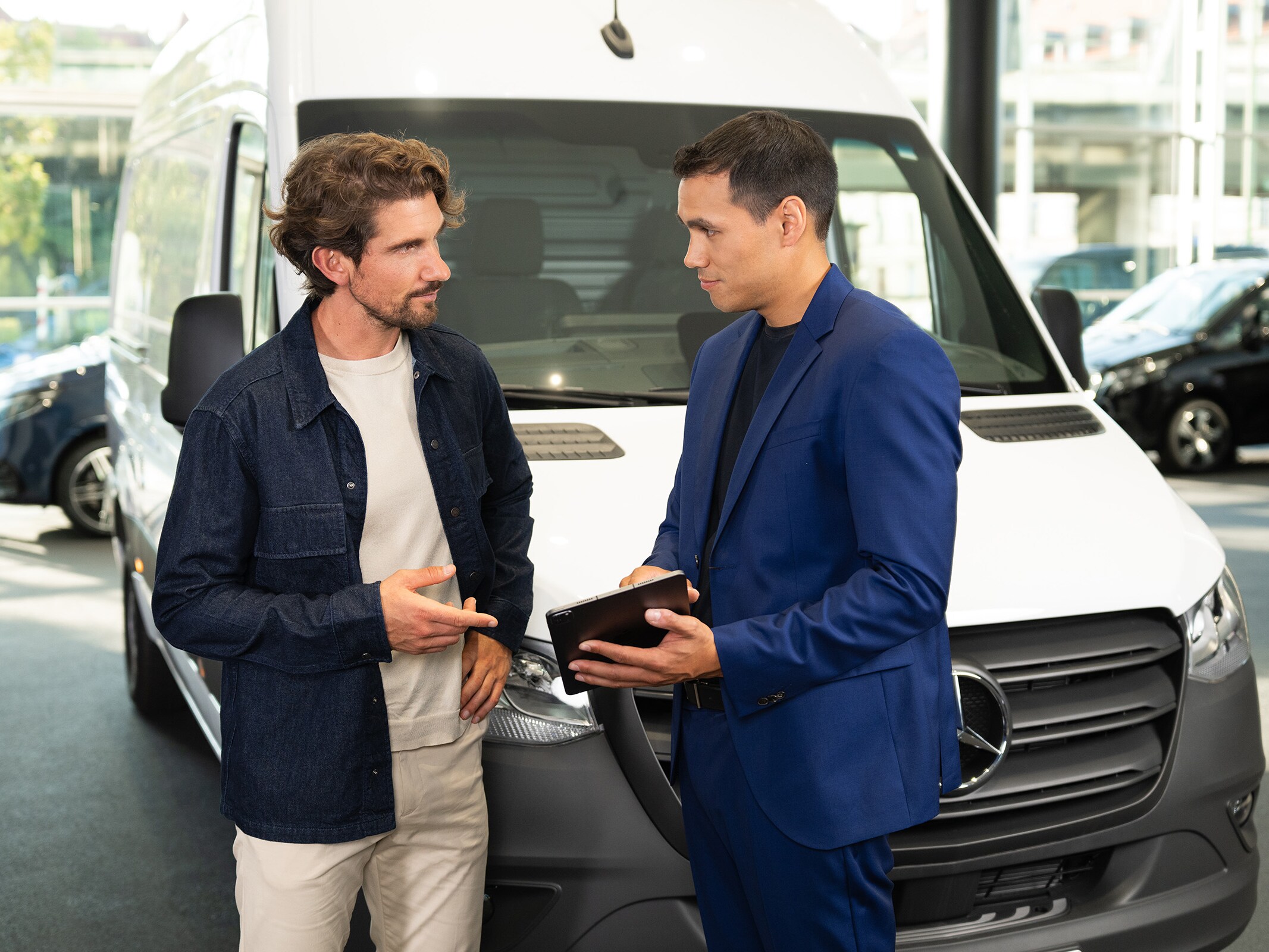 Adviesgesprek over Mercedes-Benz-bedrijfsvoertuigen in een showroom, waarbij de nadruk ligt op klantgerichte service.