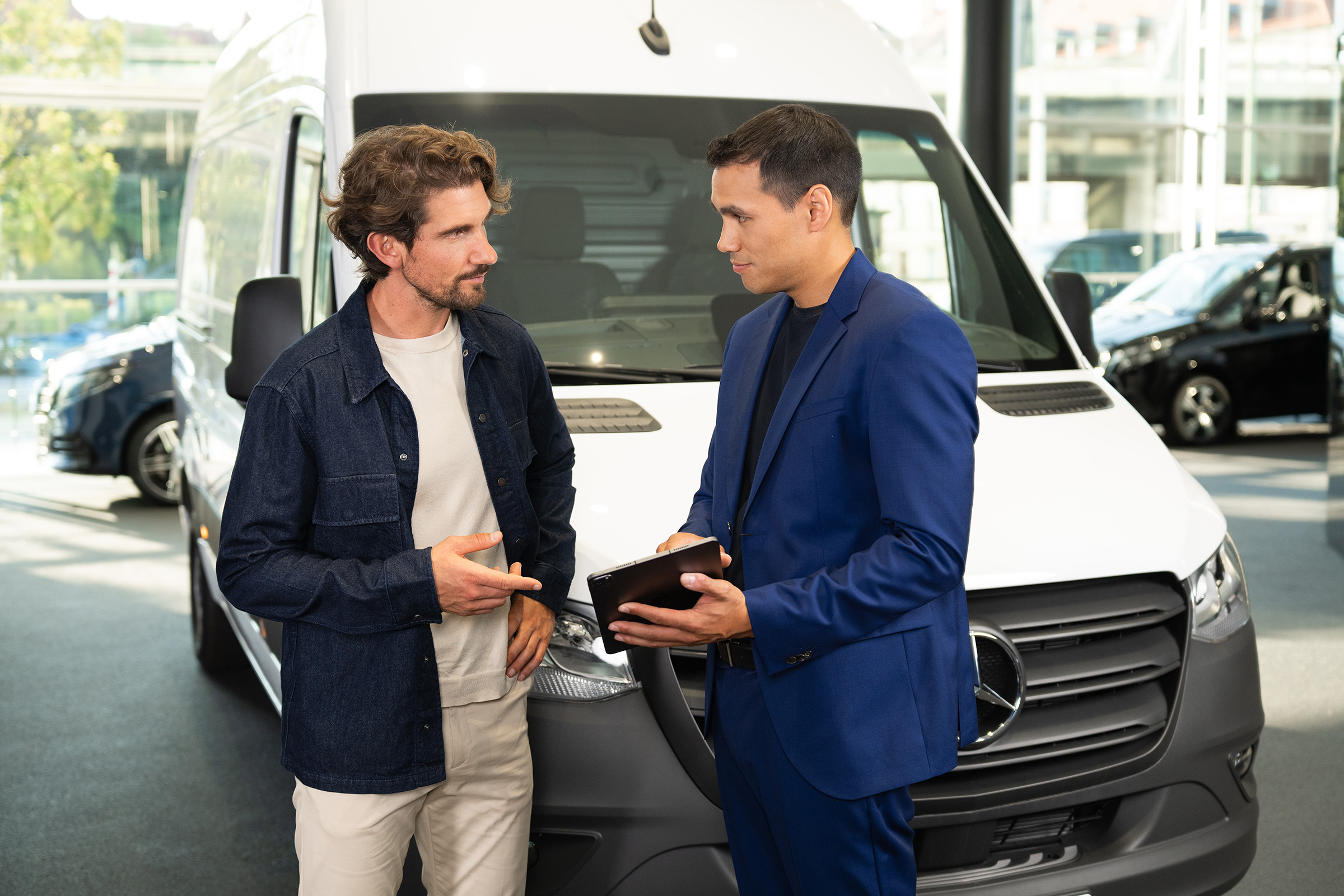 Financieringsleasing | Elektrische modellen | Mercedes-Benz Adviesgesprek over Mercedes-Benz-bedrijfsvoertuigen in een showroom, waarbij de nadruk ligt op klantgerichte service.