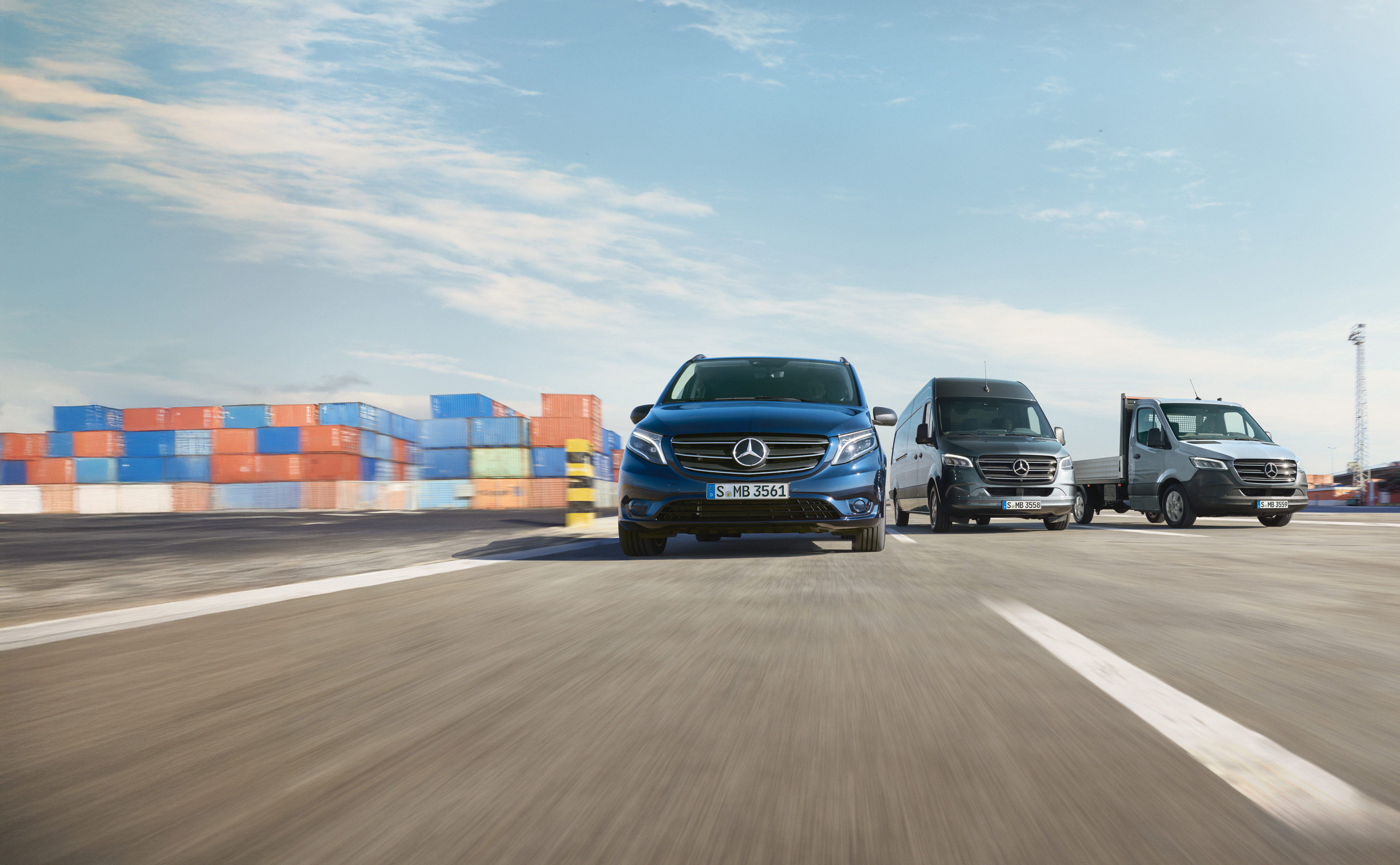 Mercedes-Benz | Van Care | Service24h Een reeks Mercedes-Benz bedrijfswagens die naast elkaar geparkeerd staan op een weg naast een laadkade.