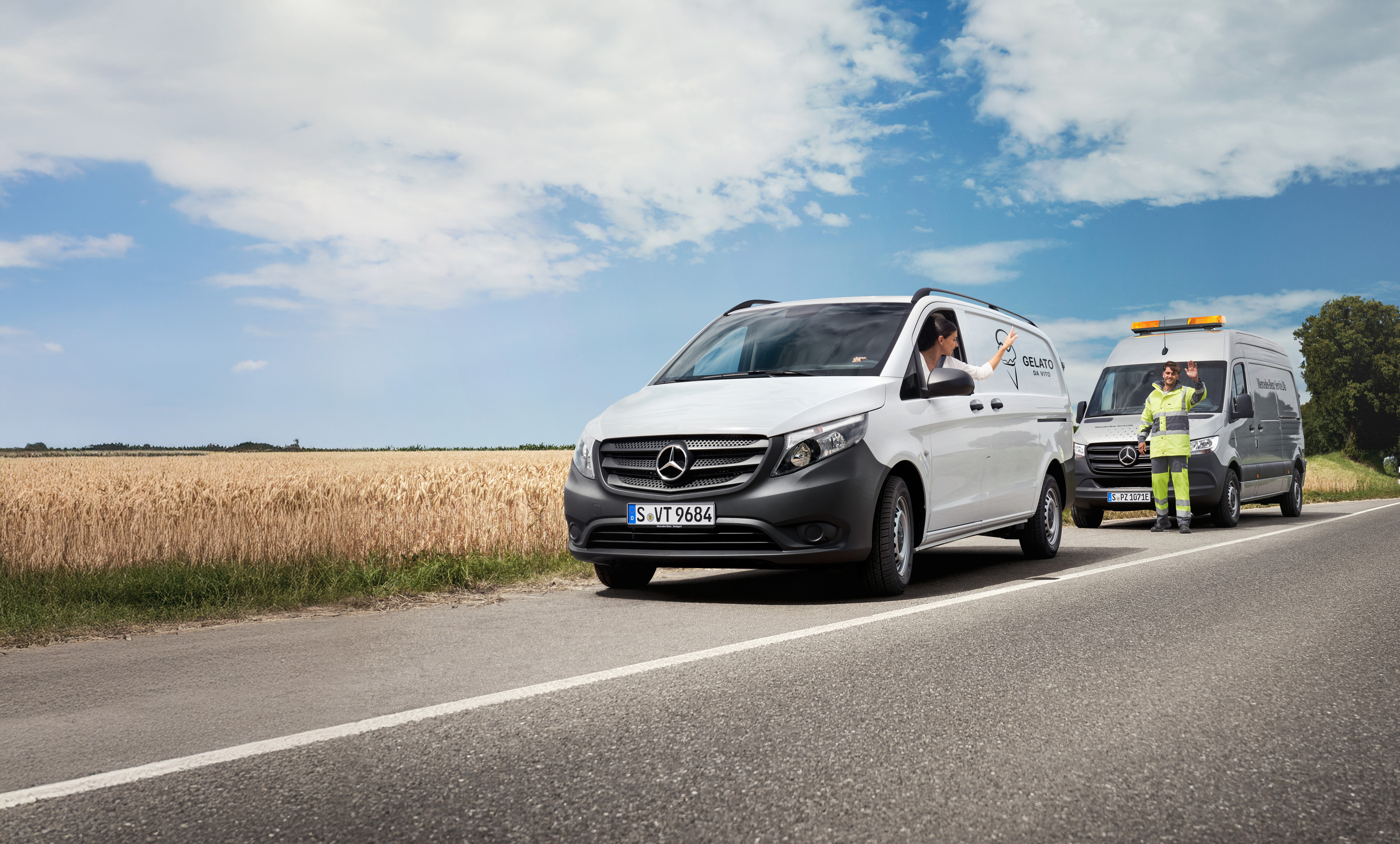 Mercedes Benz | Comfort | Mobilovan Een vrouw in een witte Mercedes-Benz Vito zwaait naar een Mercedes-Benz servicemonteur langs de kant van de weg.