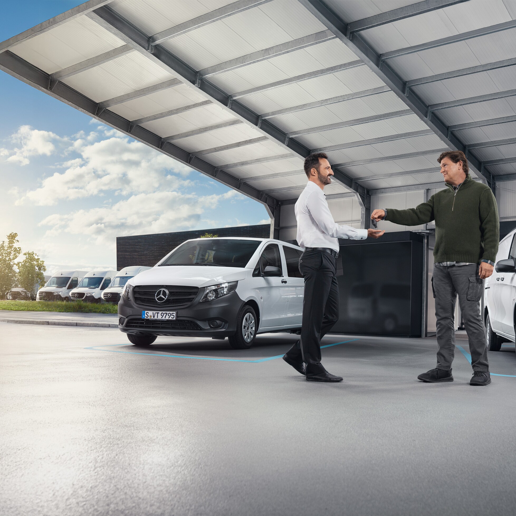 Twee mannen in gesprek voor een reeks witte Mercedes-Benz bedrijfswagens in een hal
