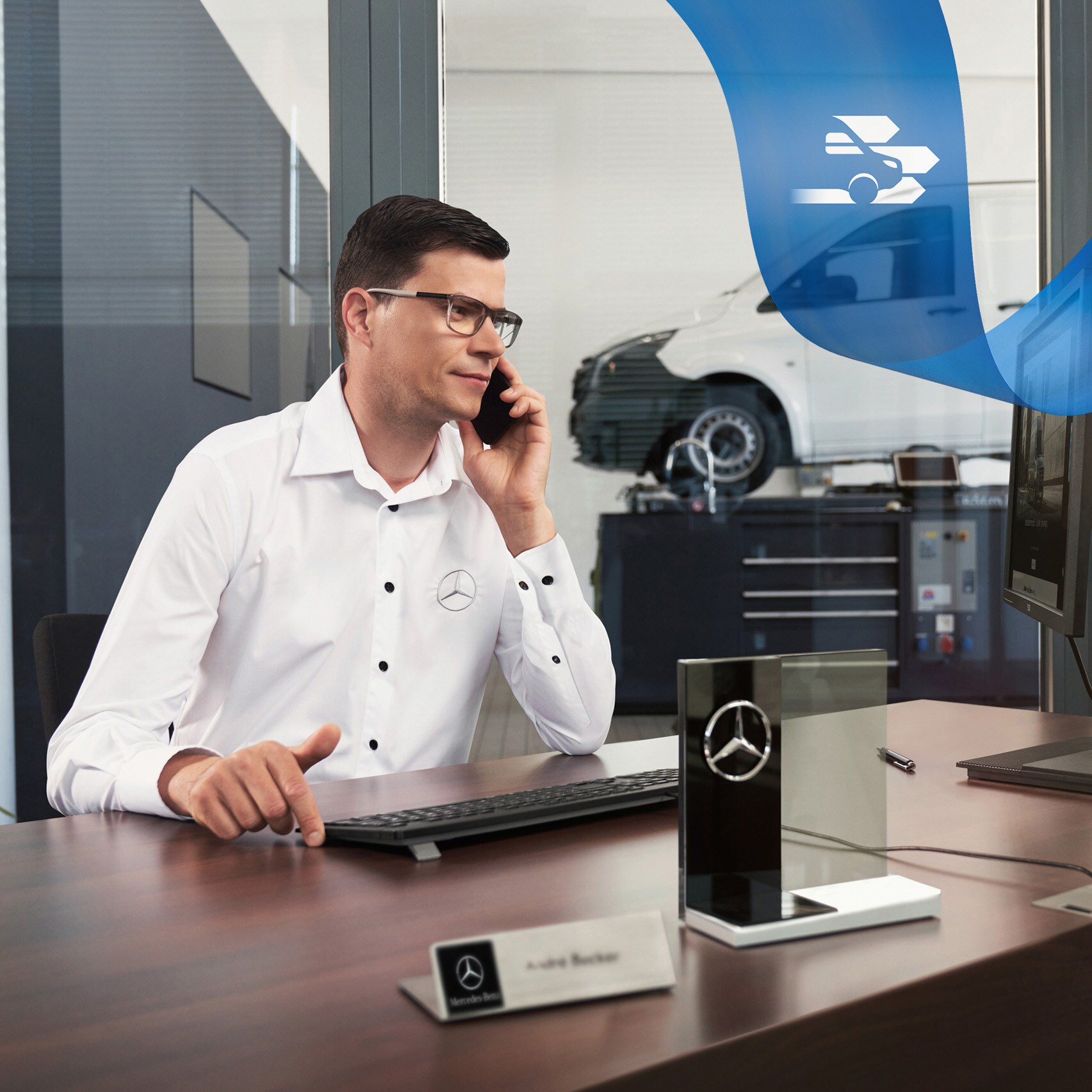 Mercedes-Benz medewerker telefoneert aan een bureau met een Mercedes-Benz Vito Gesloten Bestelwagen in de werkplaats.