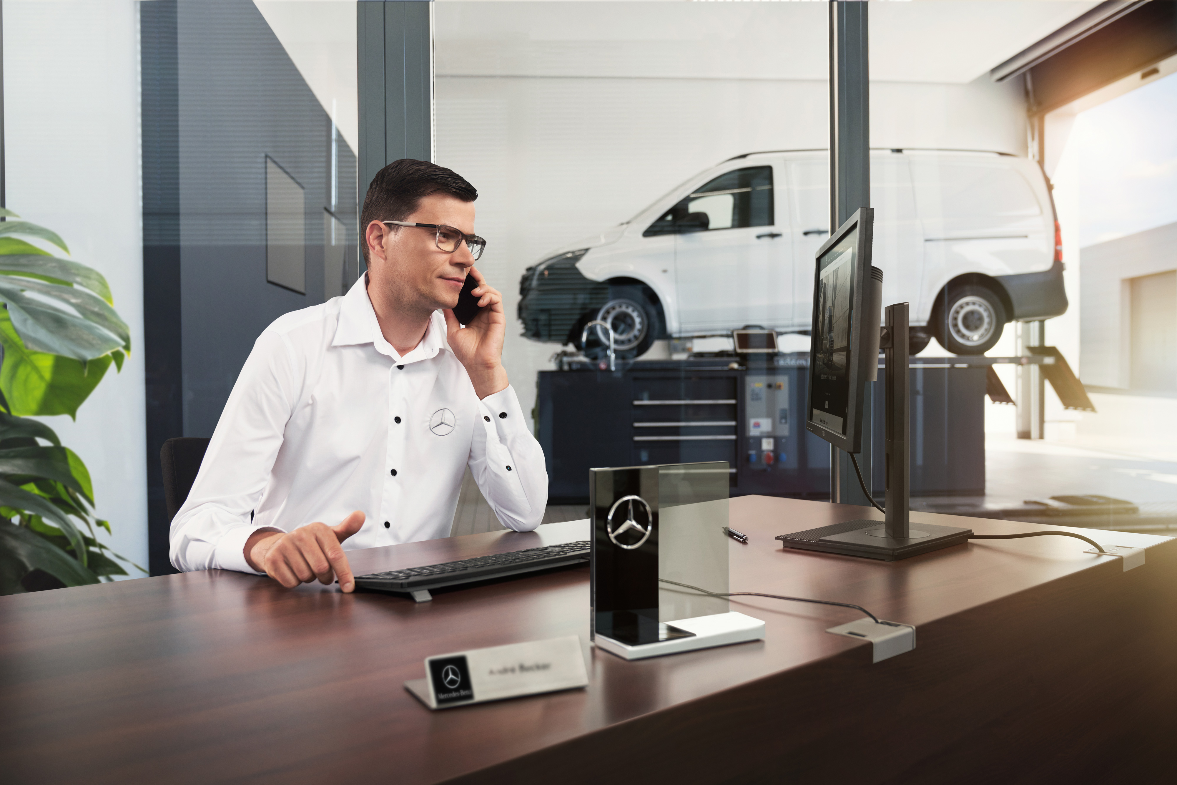 Mercedes-Benz | Comfort | Service Partner Mercedes-Benz serviceadviseur die in een werkplaats telefoneert.