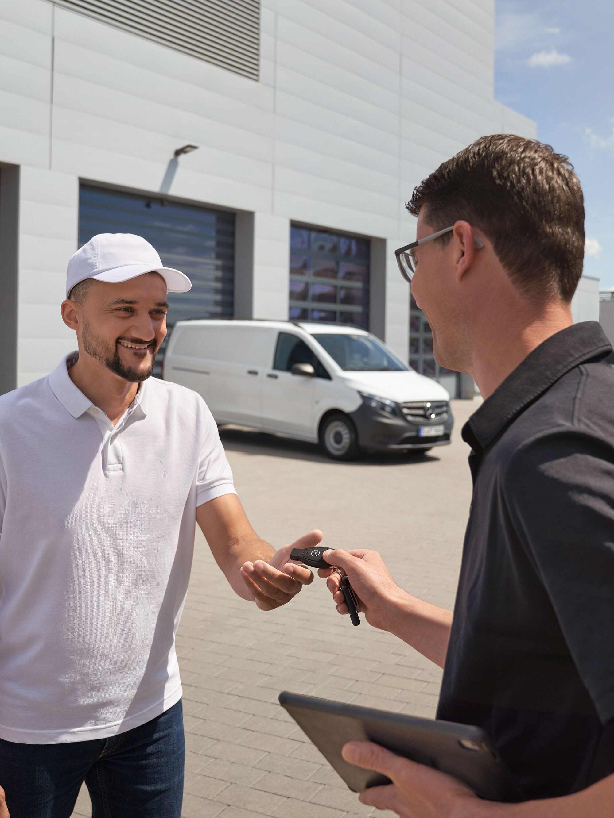 Technicien Mercedes-Benz remettant les clés à un client, avec un utilitaire léger Mercedes-Benz Vito blanc à l'arrière-plan.