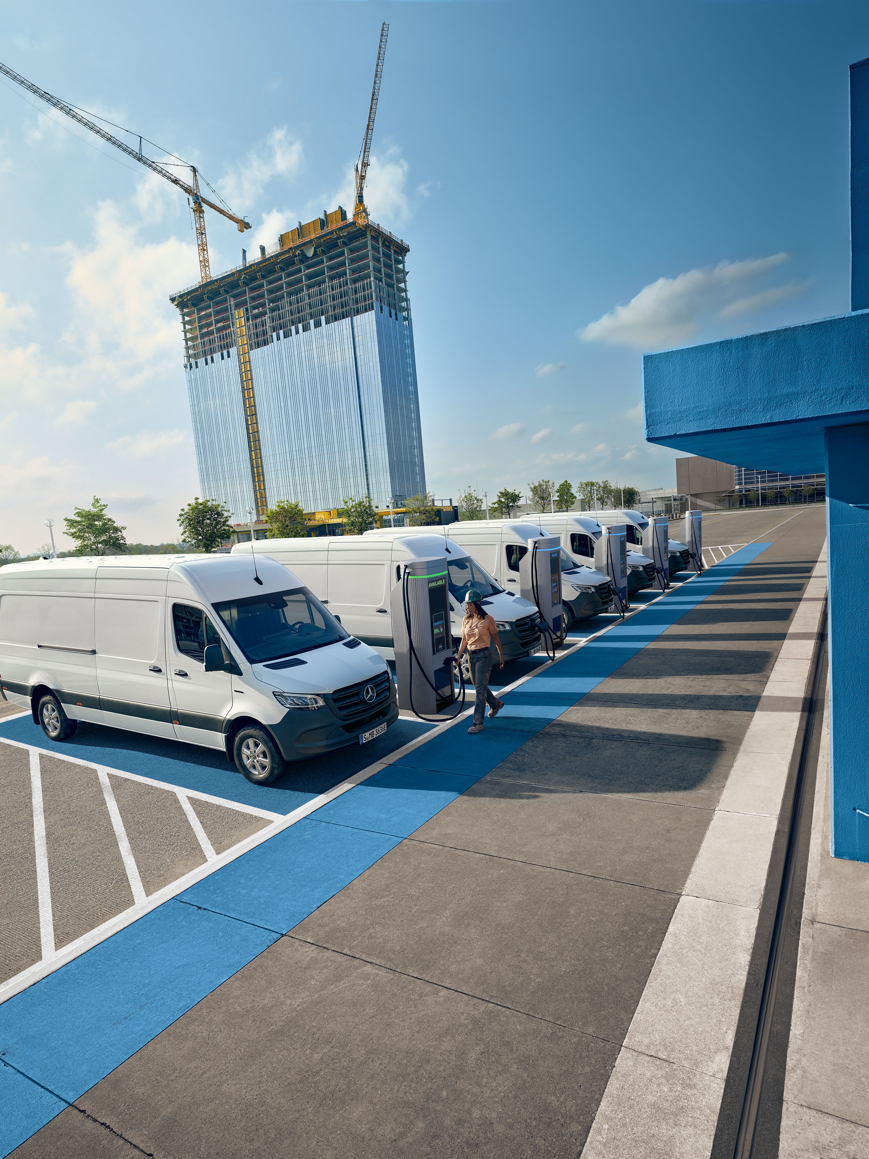 Une flotte d’utilitaires légers électriques Mercedes-Benz blancs garés à une borne de recharge.
