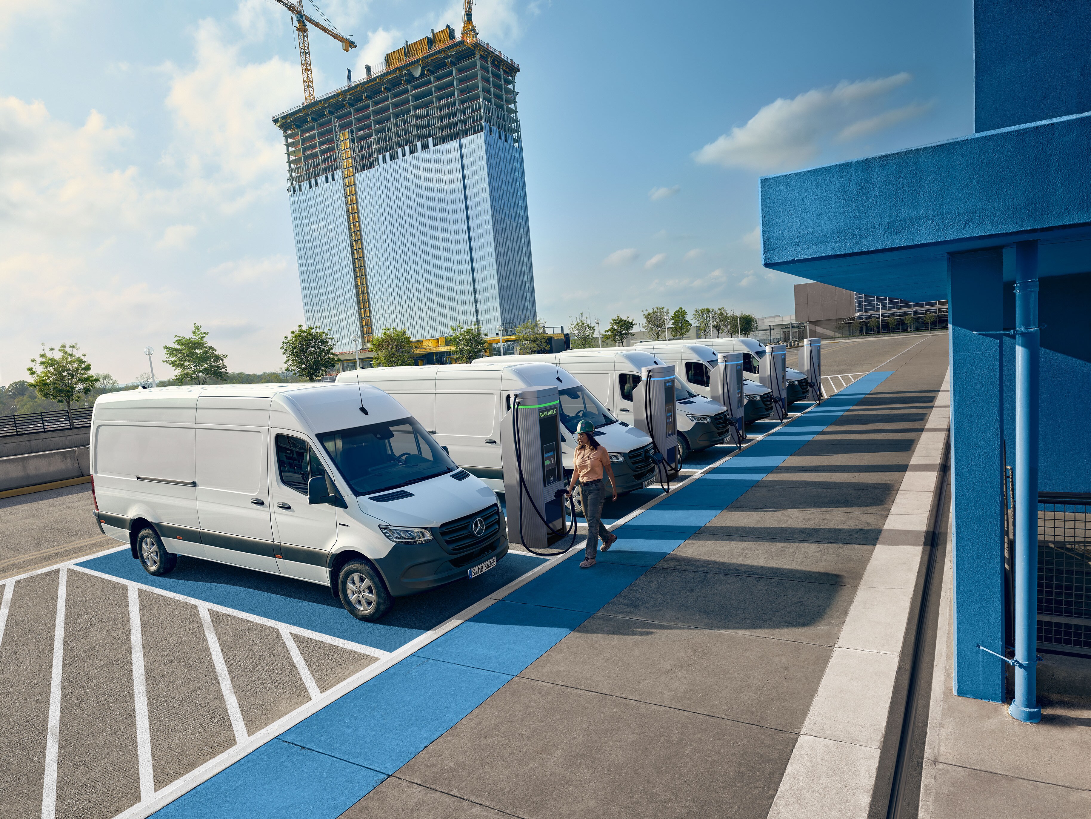 Een vloot witte elektrische Mercedes-Benz bedrijfswagens geparkeerd bij een laadstation.