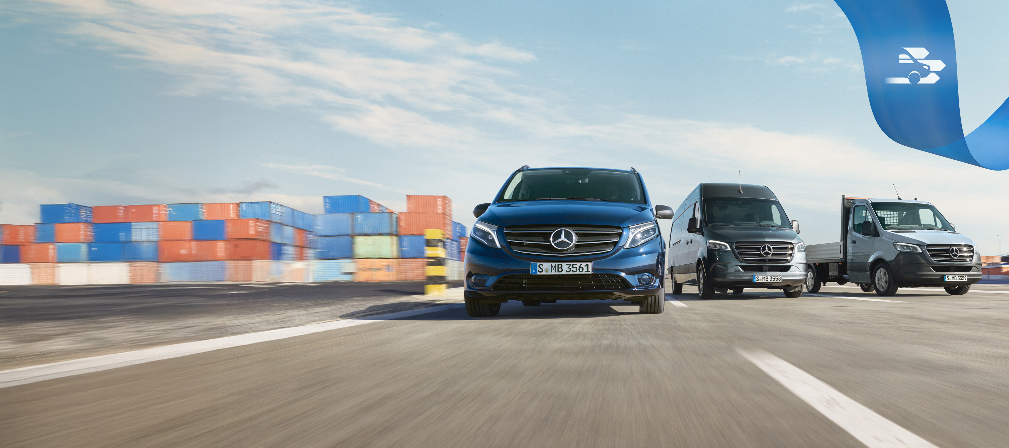 Mercedes Benz | Confort Mobilovan Une gamme d'utilitaires légers Mercedes-Benz sur la route avec des conteneurs d'expédition en arrière-plan.