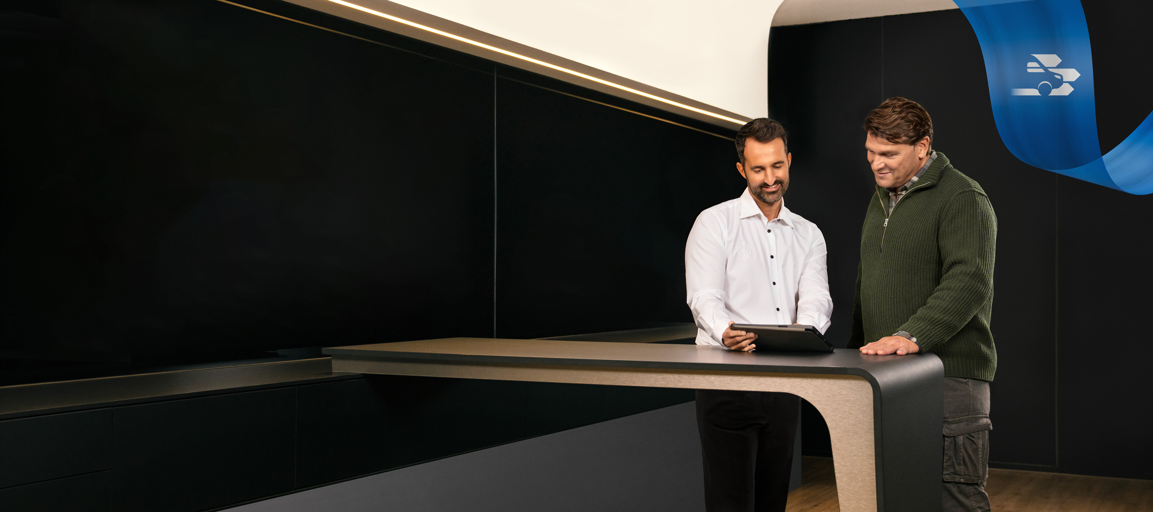 Mercedes-Benz | Confort | Partenaire de service Deux hommes debout dans le bureau d'un partenaire de service Mercedes-Benz, discutant de quelque chose qu’ils ont vu sur une tablette