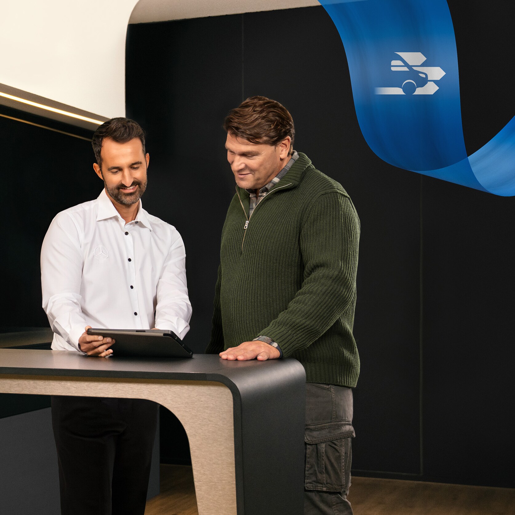 Twee mannen in een Mercedes-Benz servicepartnerkantoor die iets bespreken dat op een tablet te zien is