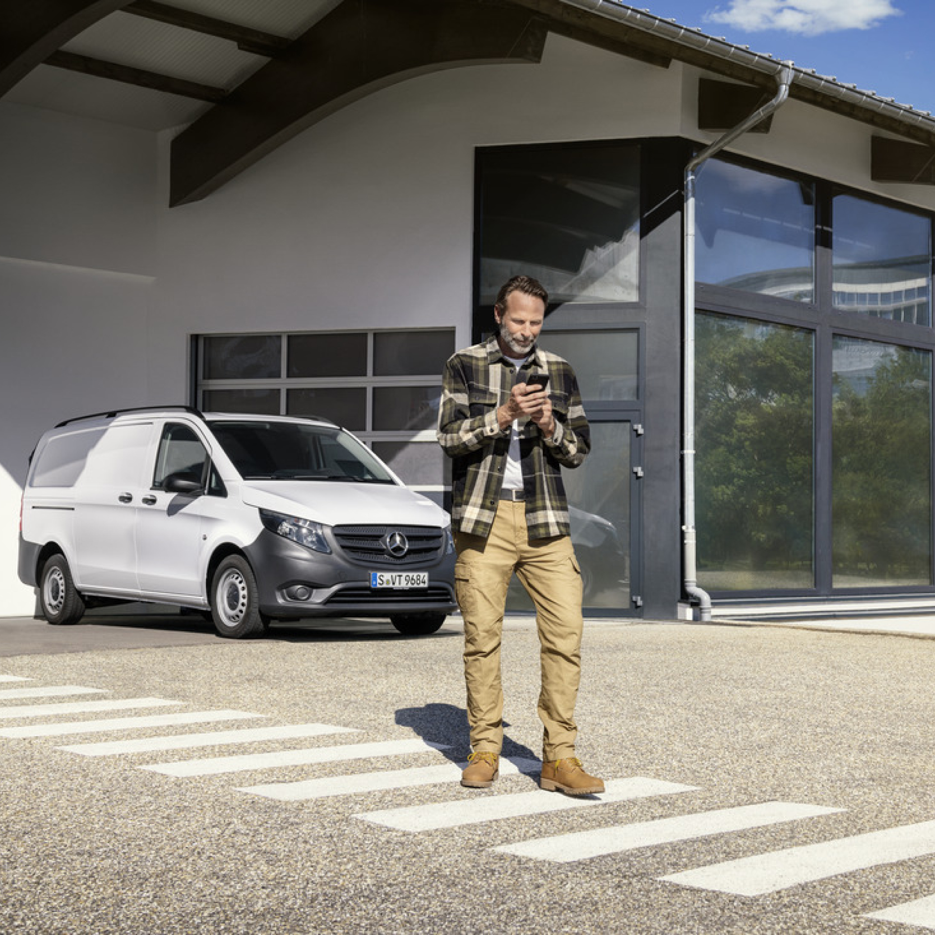 Mercedes-Benz Store | Offres digitales | Mercedes-Benz Une personne avec un smartphone devant un Mercedes-Benz Vito.