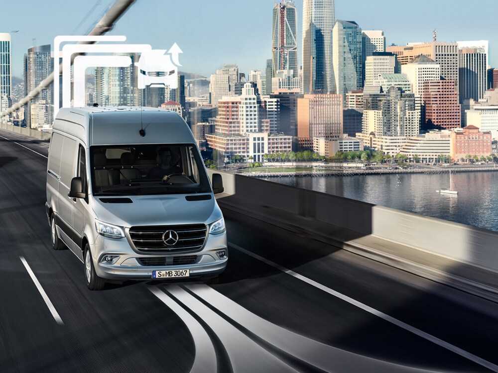 Un utilitaire léger Mercedes-Benz traverse un pont à plusieurs voies en plein jour.